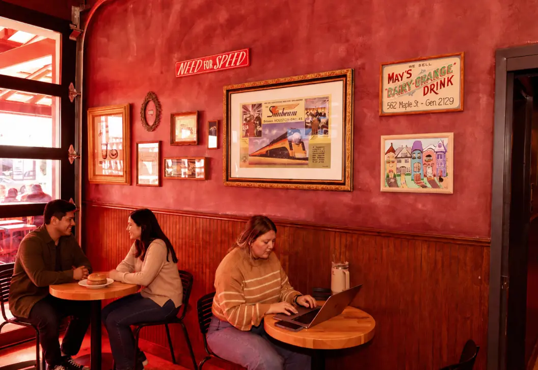 Inside of Sunbeam Bagel & Coffee Co. with patrons sitting at tables eating bagels and working on a laptop