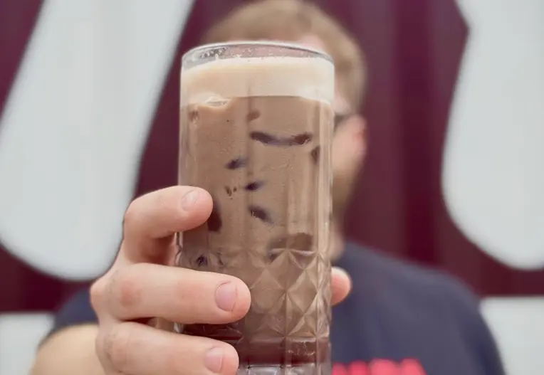 Man holding an iced coffee in a glass