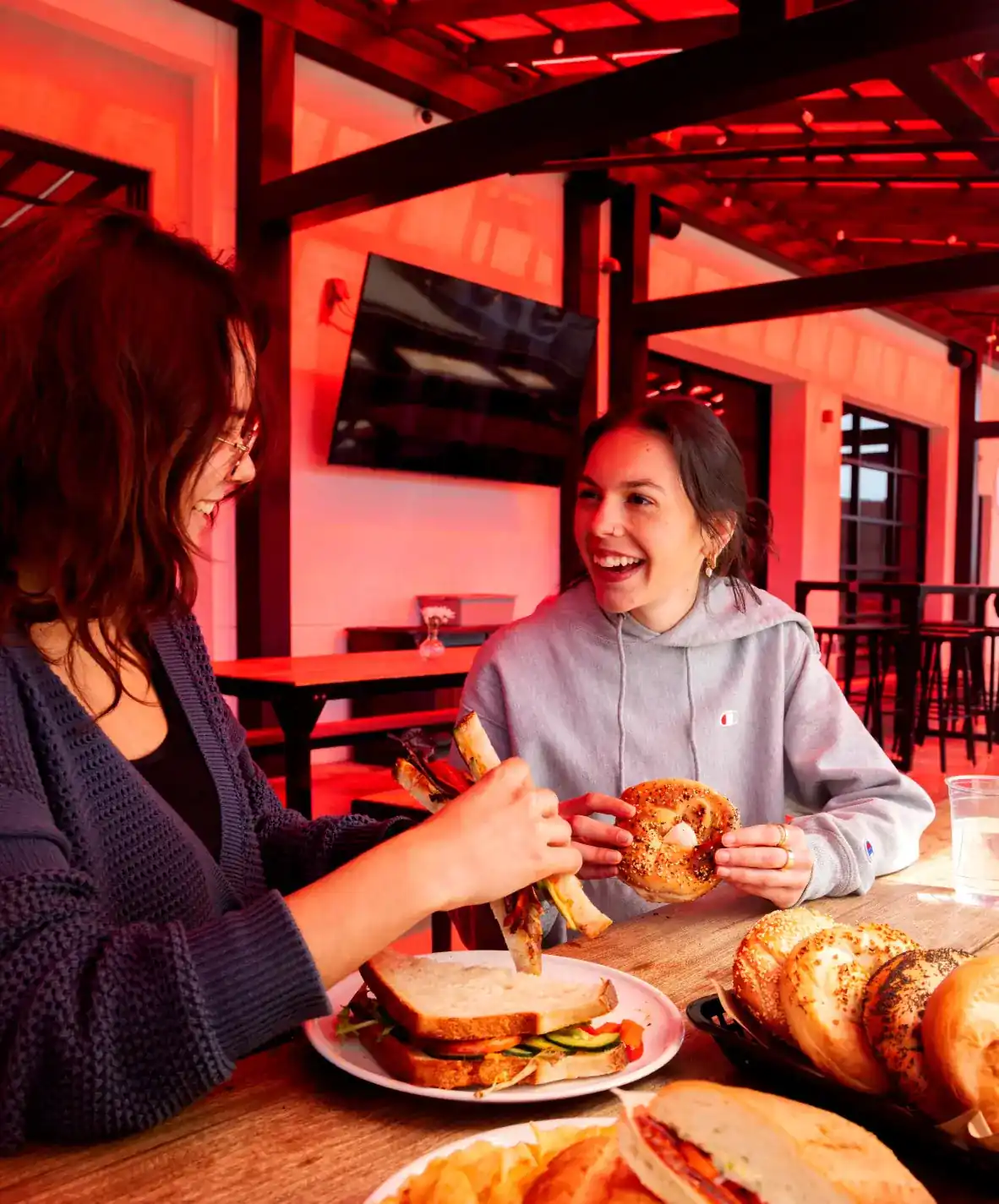 Two women sitting on the patio of Sunbeam eating sandwiches and bagels