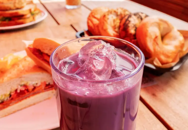 Bagels, sandwiches, and an iced coffee sitting on a table.