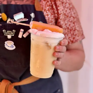 Hand holding iced coffee topped with cold foam