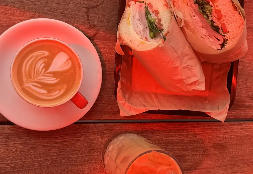 Cappuccino with foam art next to a sandwich