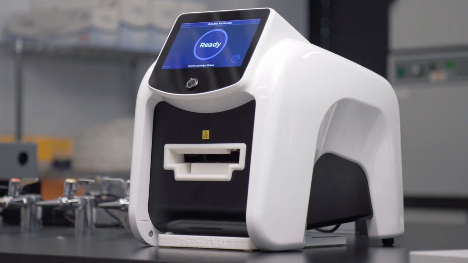 White and black lab device with touchscreen showing 'Ready' message in a laboratory setting.