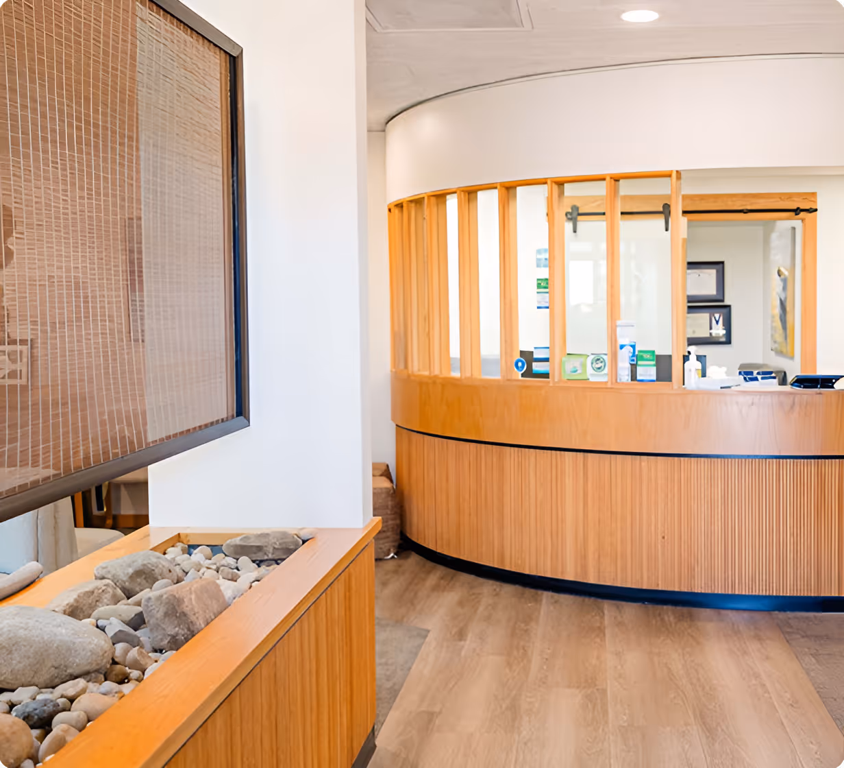 Reception area with curved wooden desk, glass panel windows, and stone decoration on a wooden stand.