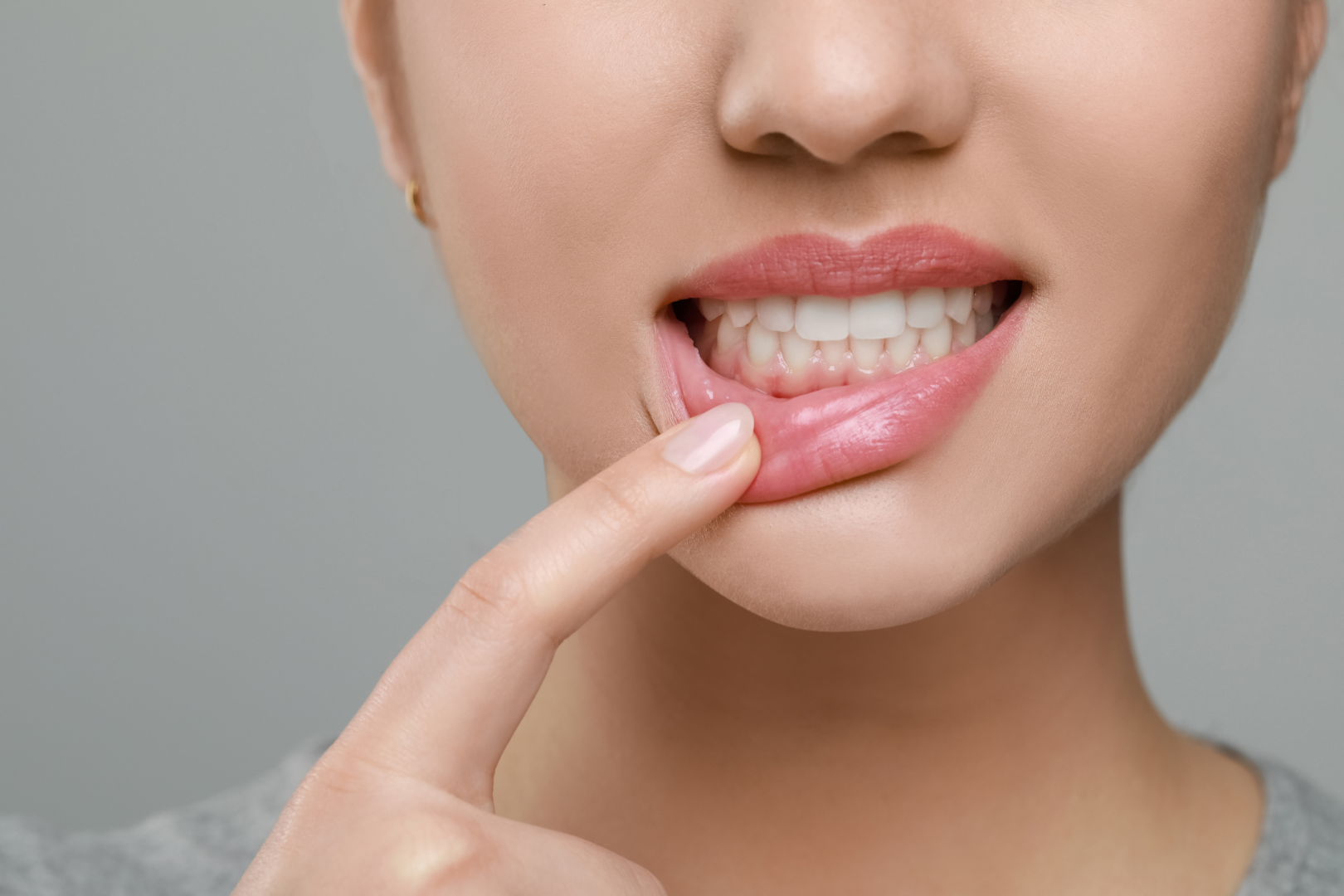 Close-up of a person pulling down their lower lip to show healthy teeth and gums.