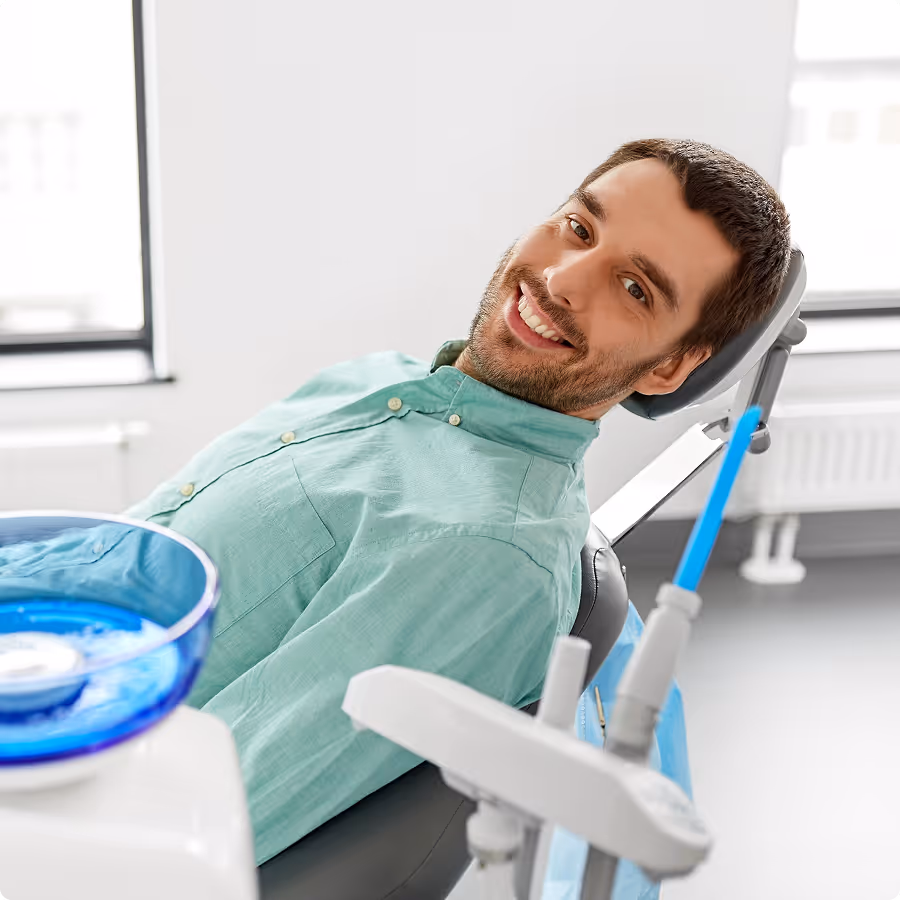 Smiling man reclining on a dental chair in a bright dental office.
