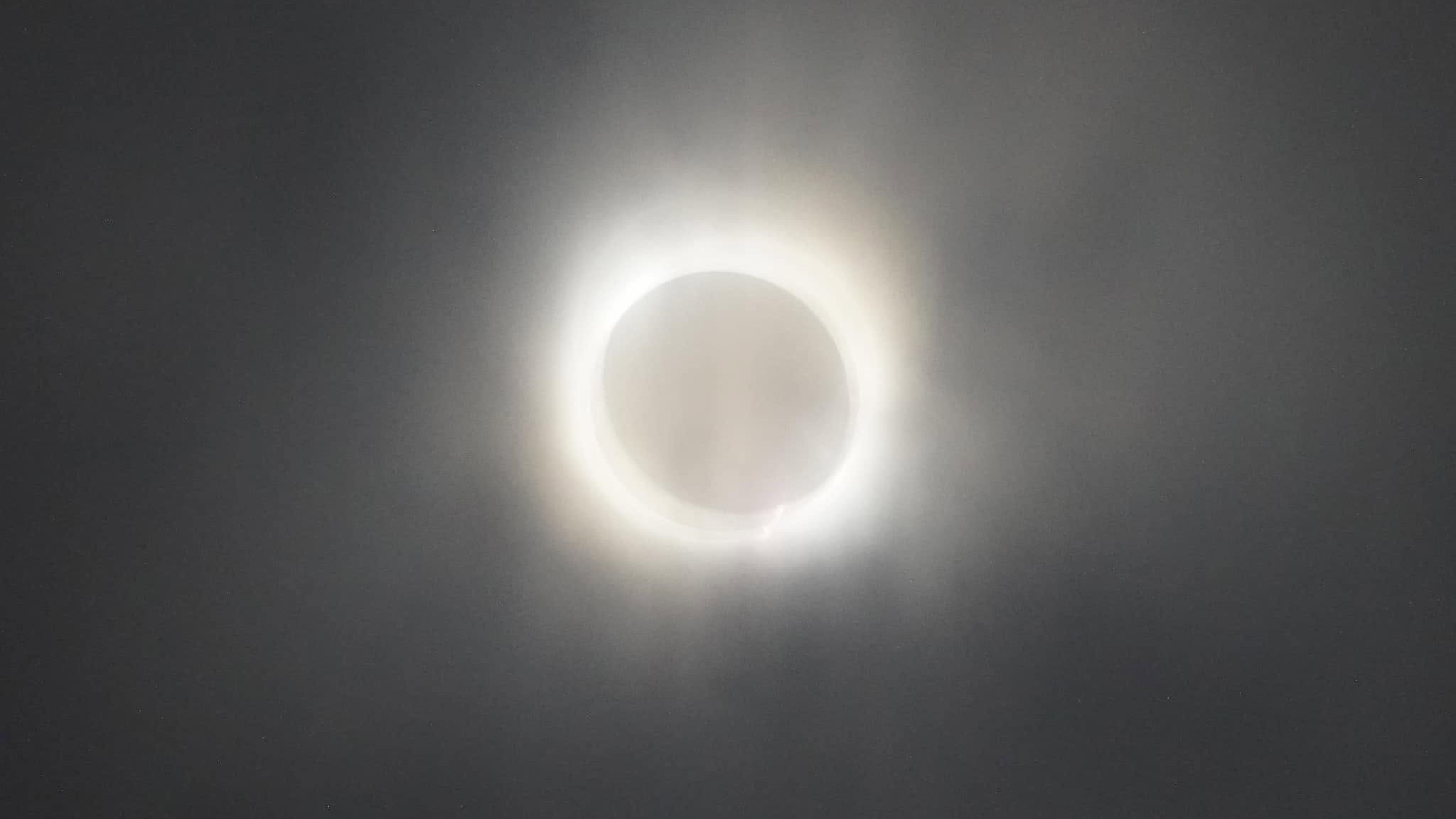 Totality over the Texas Hill Country: the Moon fully covering the Sun, the white ring of the corona glowing through thin cloud