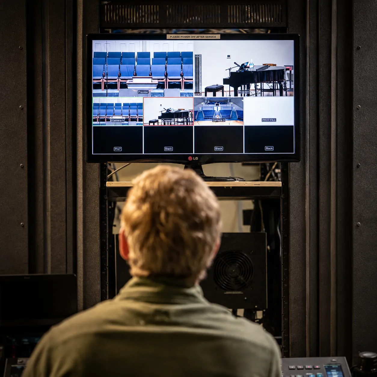Technician viewed from behind checking a multiview monitor showing sanctuary camera angles, a preview/program feed, and ProPresenter status