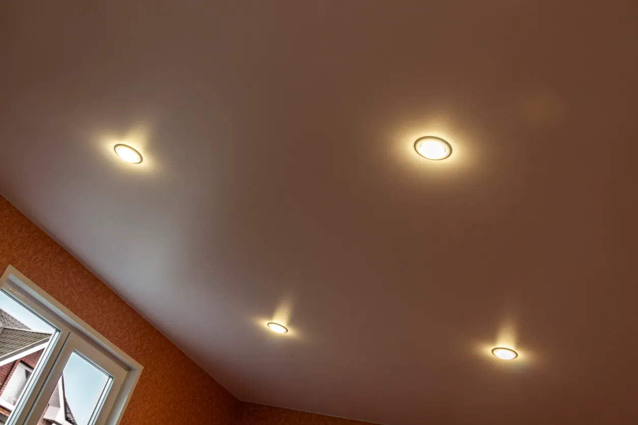 Recessed LED ceiling lights on a sloped stucco ceiling above a dormer window