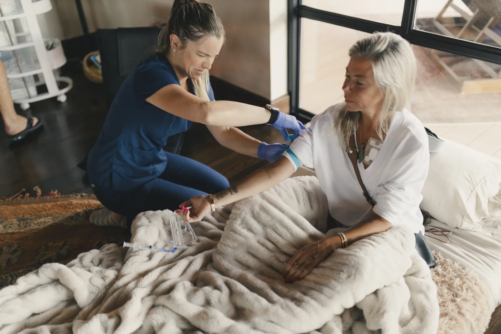A nurse starts an IV for a participant resting under a blanket