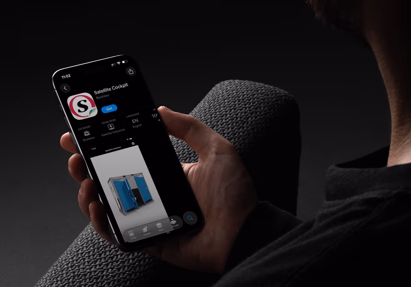 Person holding smartphone showing Satellite Cockpit app store page with blue portable restroom image