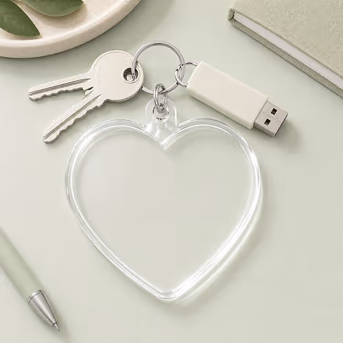 Keychain with two keys, a USB drive, and a transparent heart-shaped acrylic tag on a light surface.