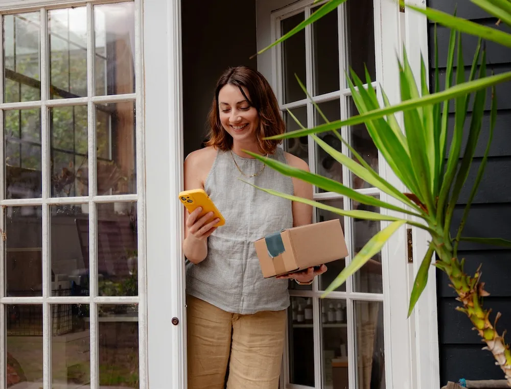 An image of a woman receiving a Clume Health weight loss package at her front door.