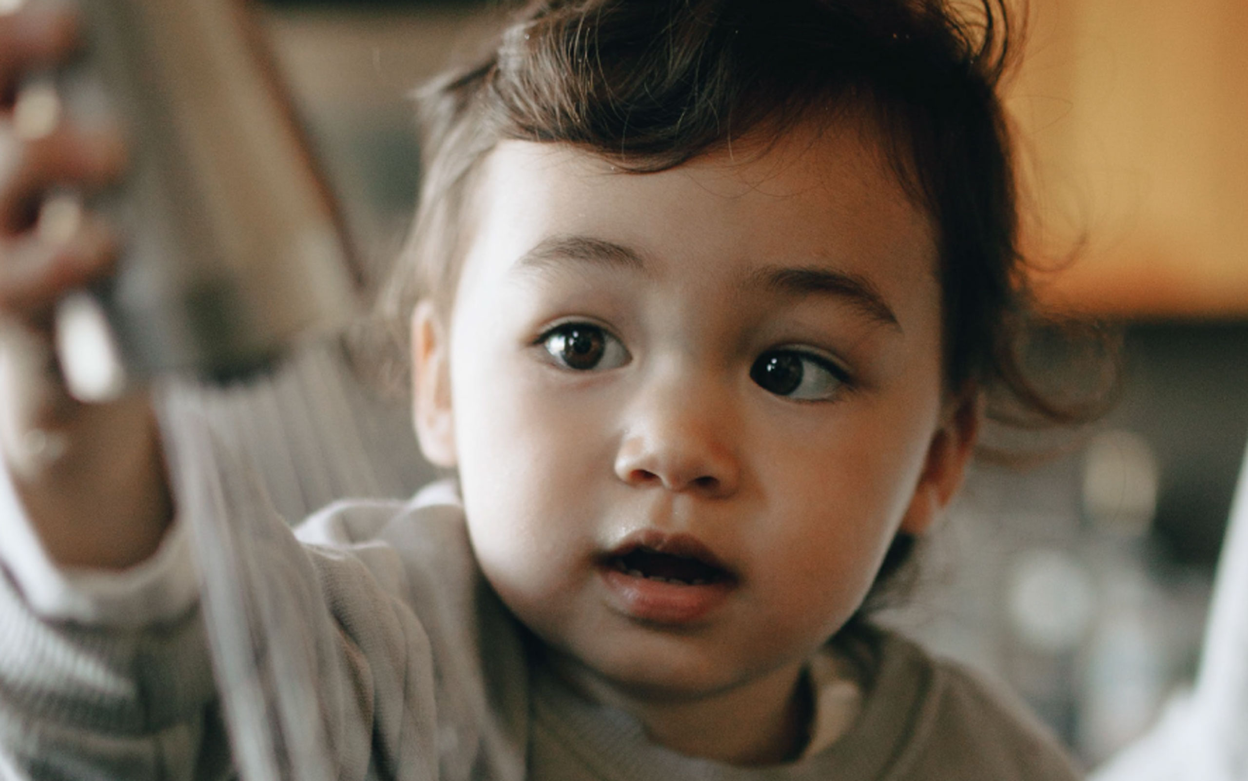 A young child gazes off-camera in a warmly lit home