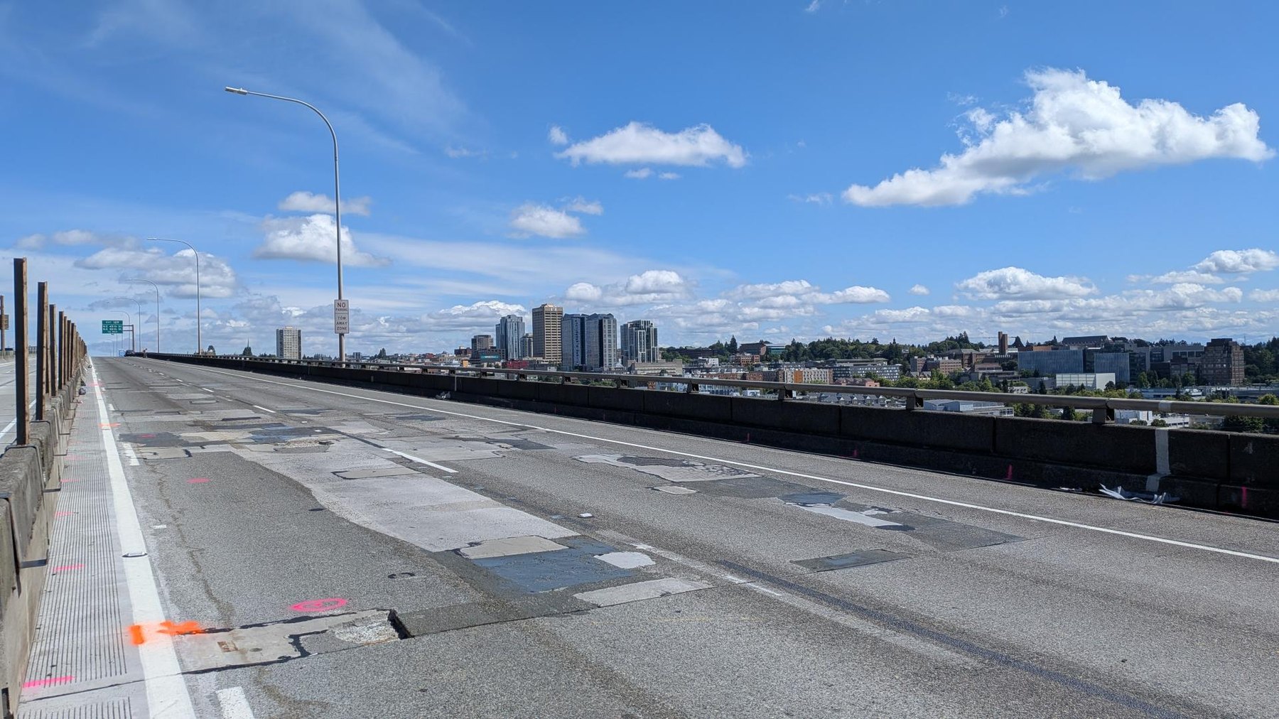 The worn and patched upper deck of the Ship Canal Bridge before resurfacing, with the Seattle skyline in the distance