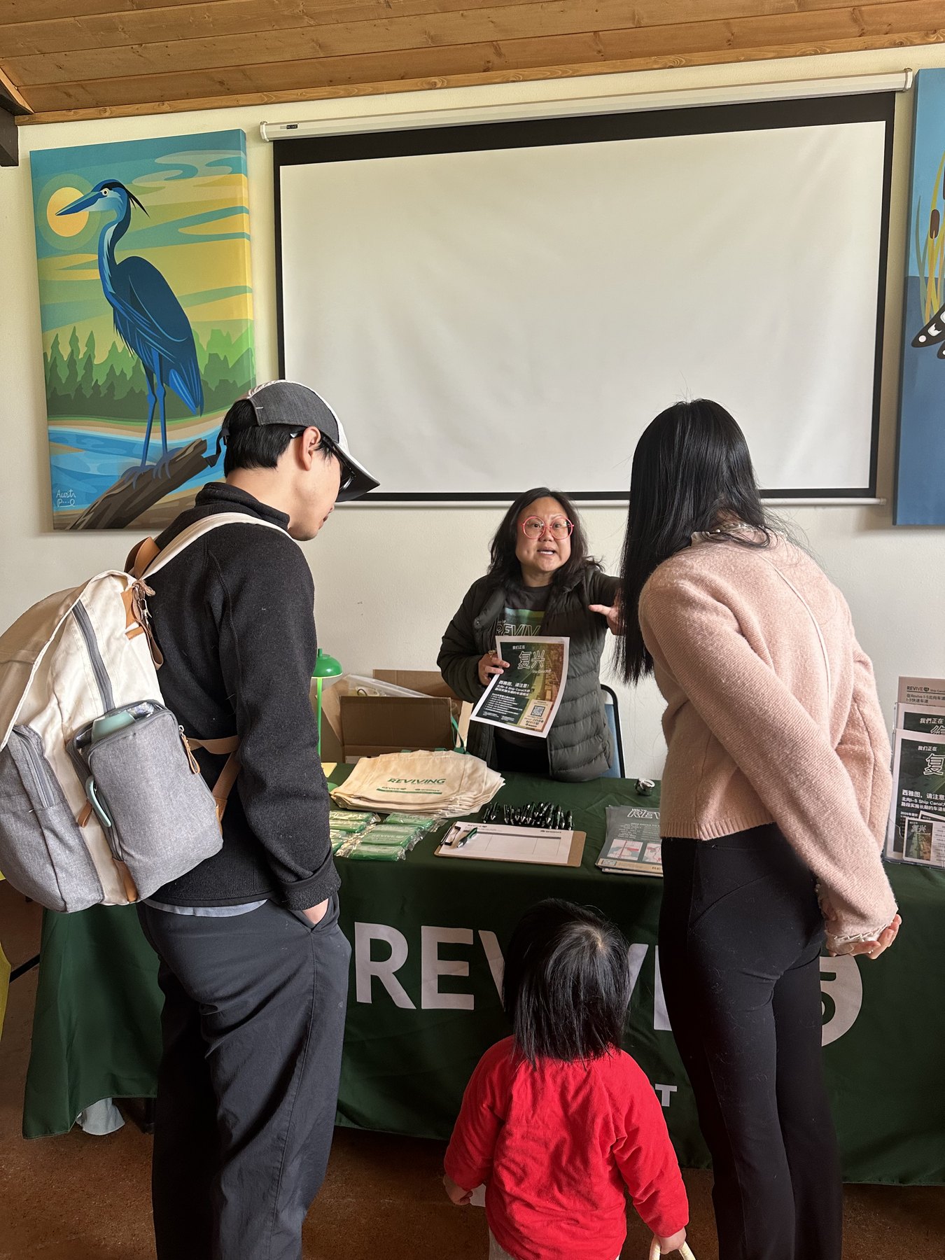 A Revive I-5 staff member speaks with visitors at a project information table during a community event