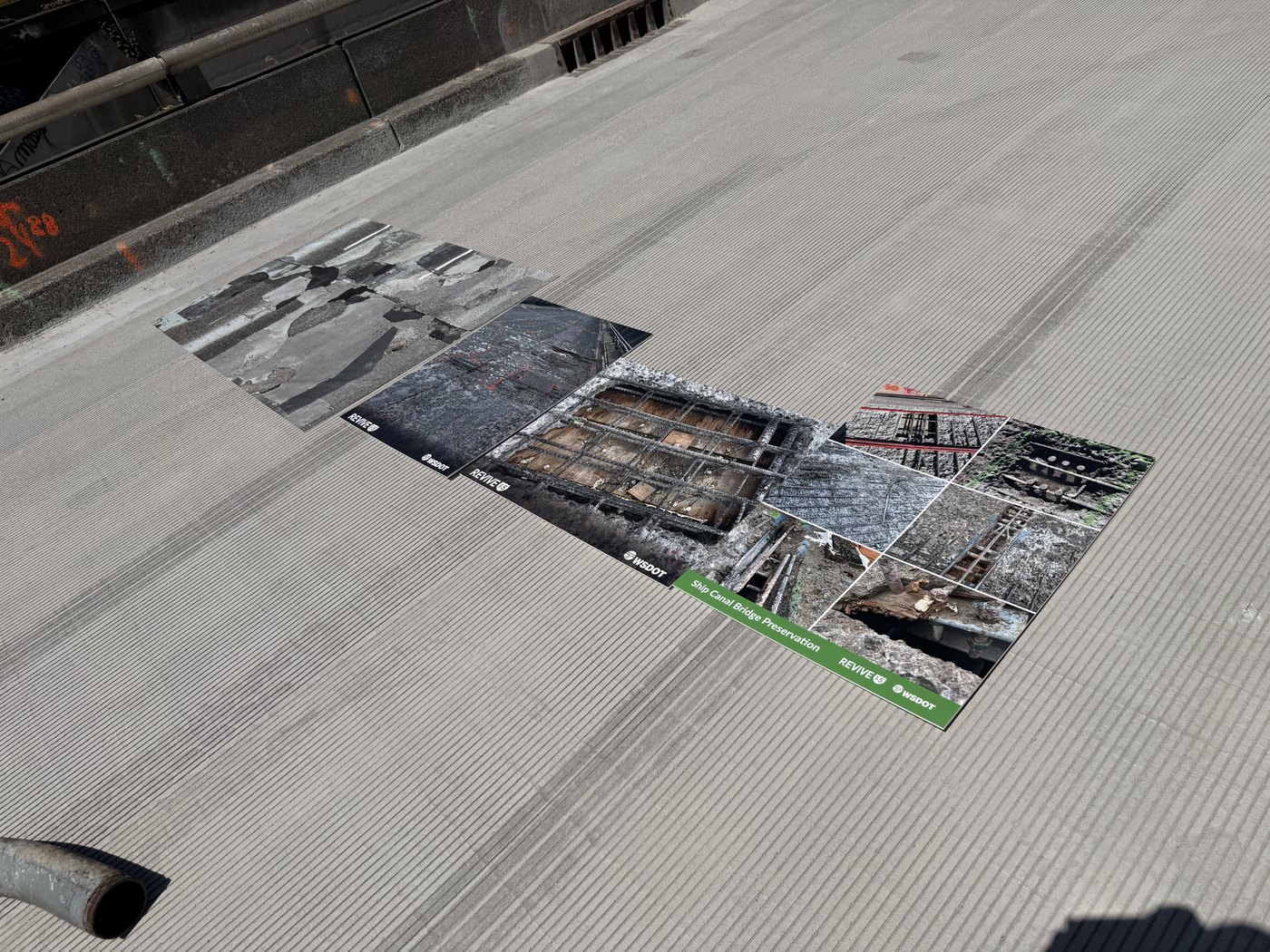 Large printed photo boards laid on the bridge deck showing deterioration found during construction