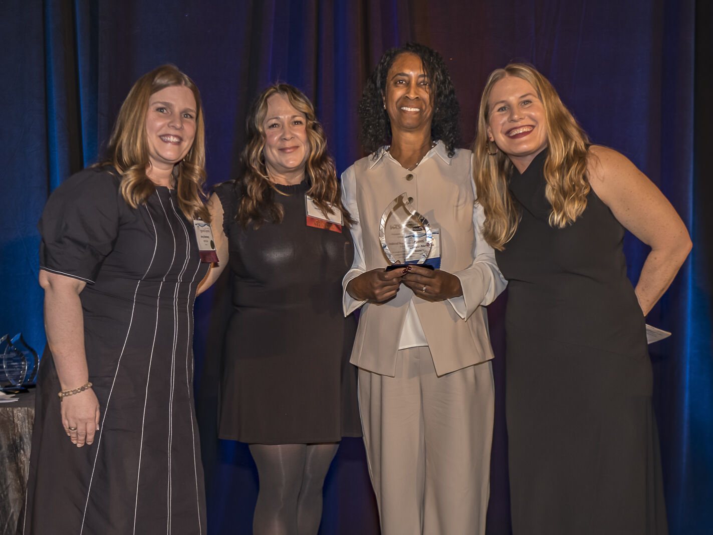 Four team members on stage at the WTS Puget Sound awards ceremony, one holding the glass award trophy.