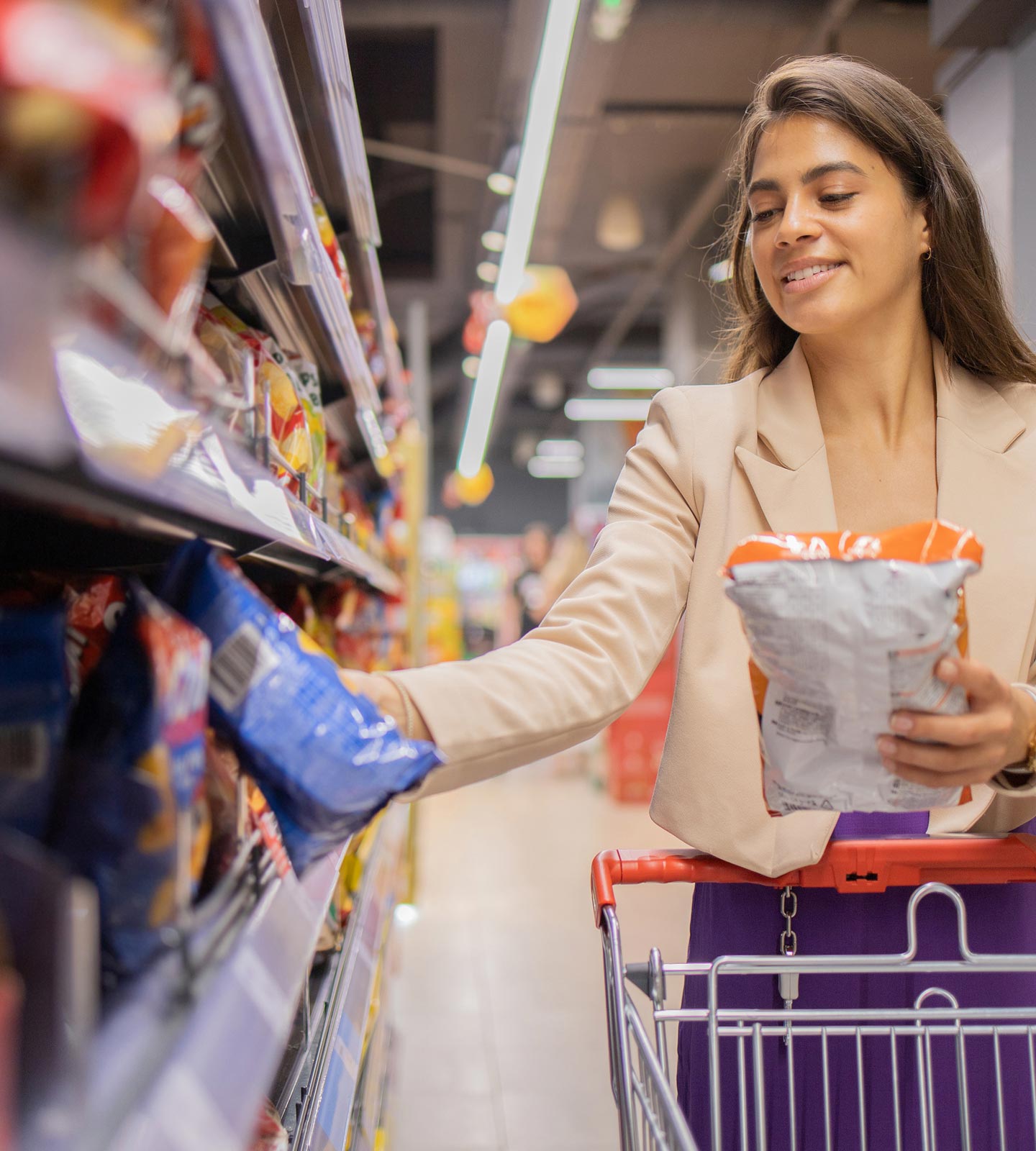 A shopper comparing two snack packages while browsing a grocery store aisle.