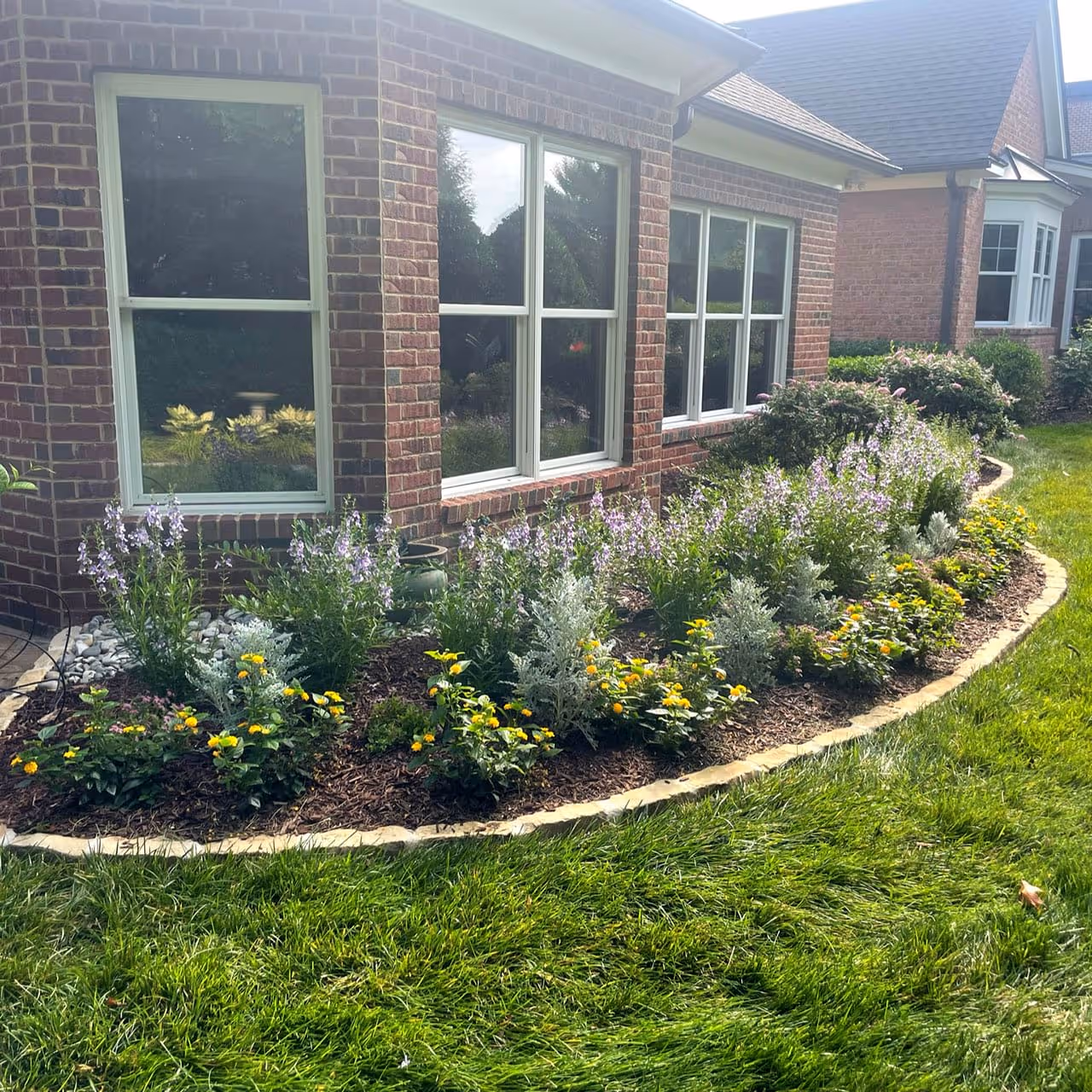 Custom landscape design with colorful plants and professionally maintained garden beds
