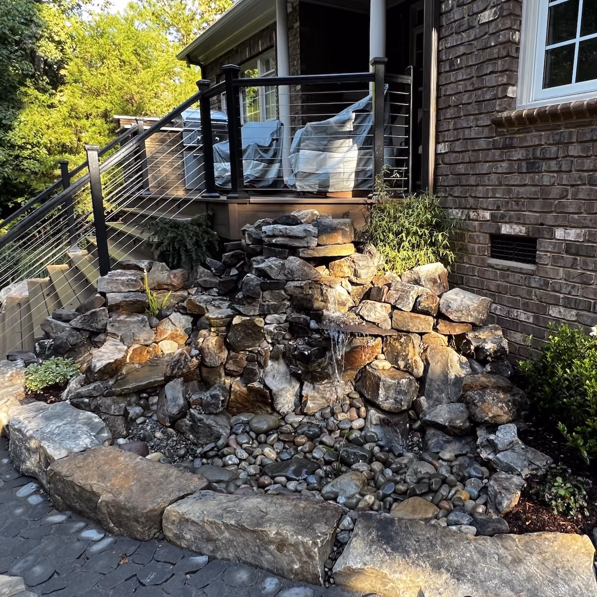 Backyard pondless waterfall designed with natural stone and plants