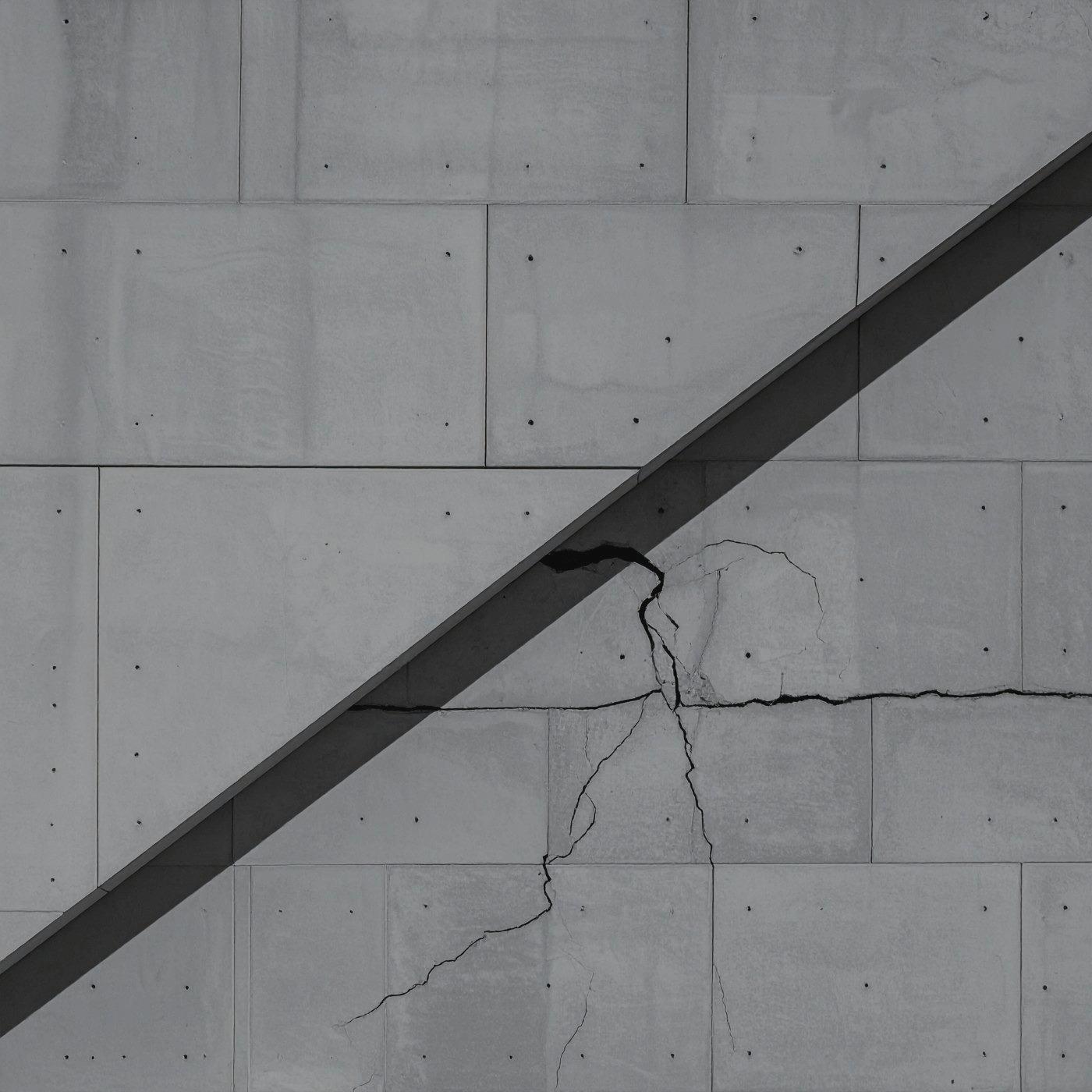 Person falling or suspended against a modern concrete building with angular structures.