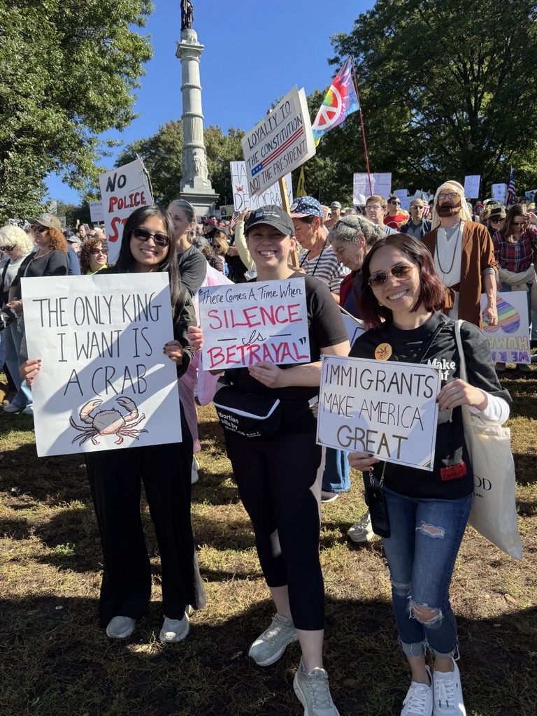 MORE team members holding handmade signs at an outdoor rally