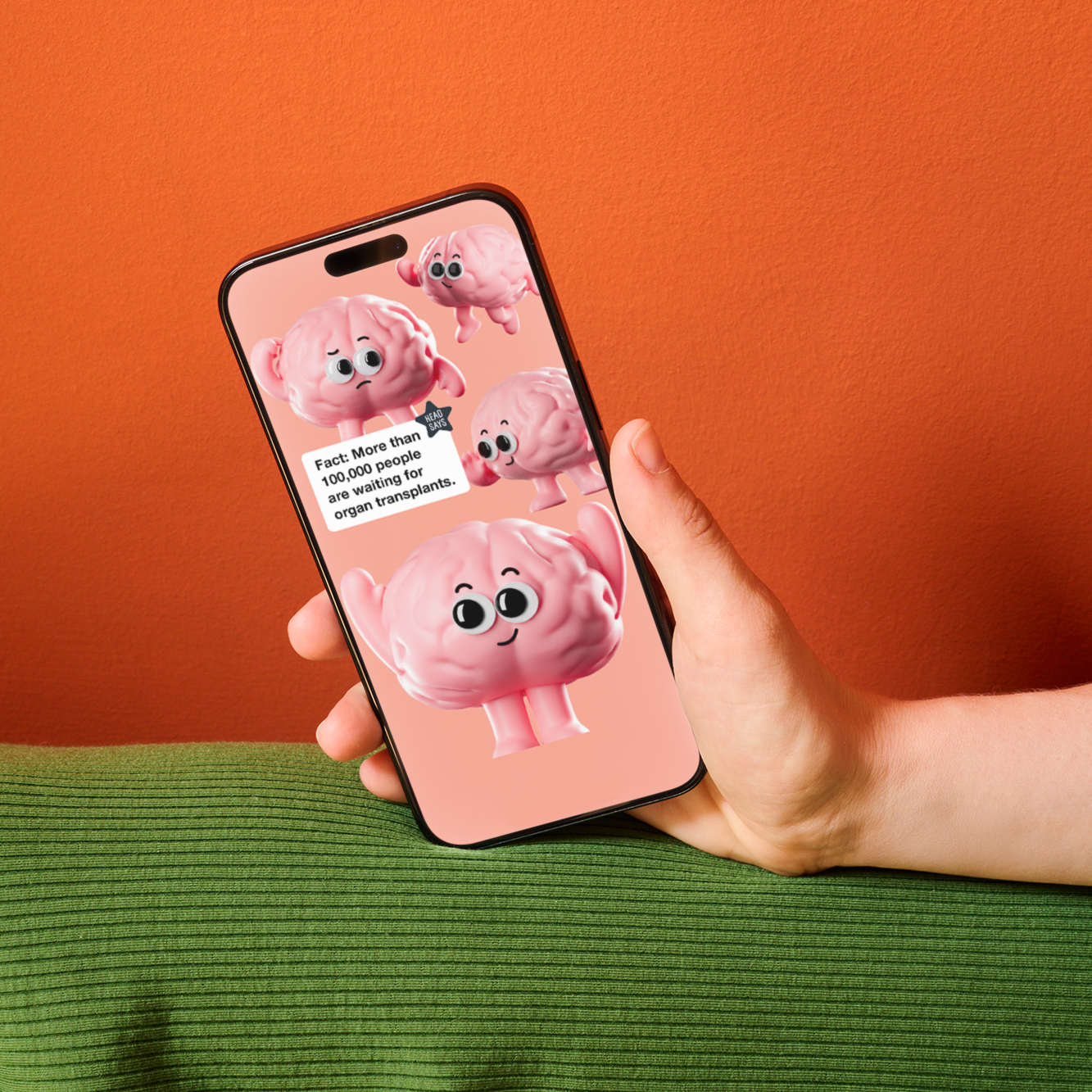 Hand holding a phone that shows an organ donor post with animated brain characters