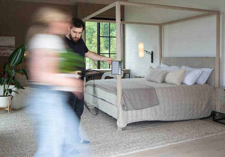 Man showing a color palette to a blurred woman inside a modern bedroom with a four-poster bed.