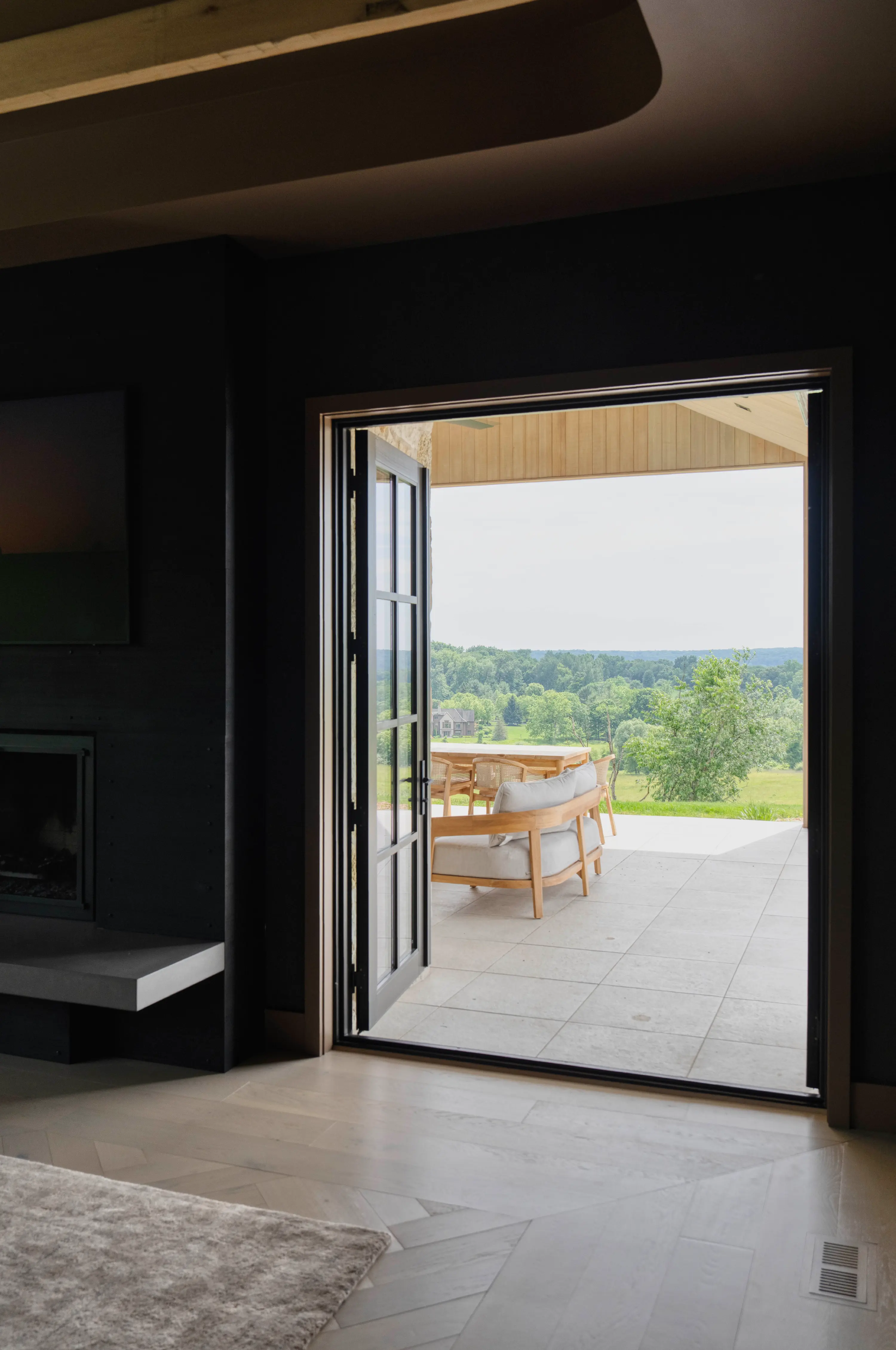 View through open patio door showing outdoor seating and green trees in the distance.