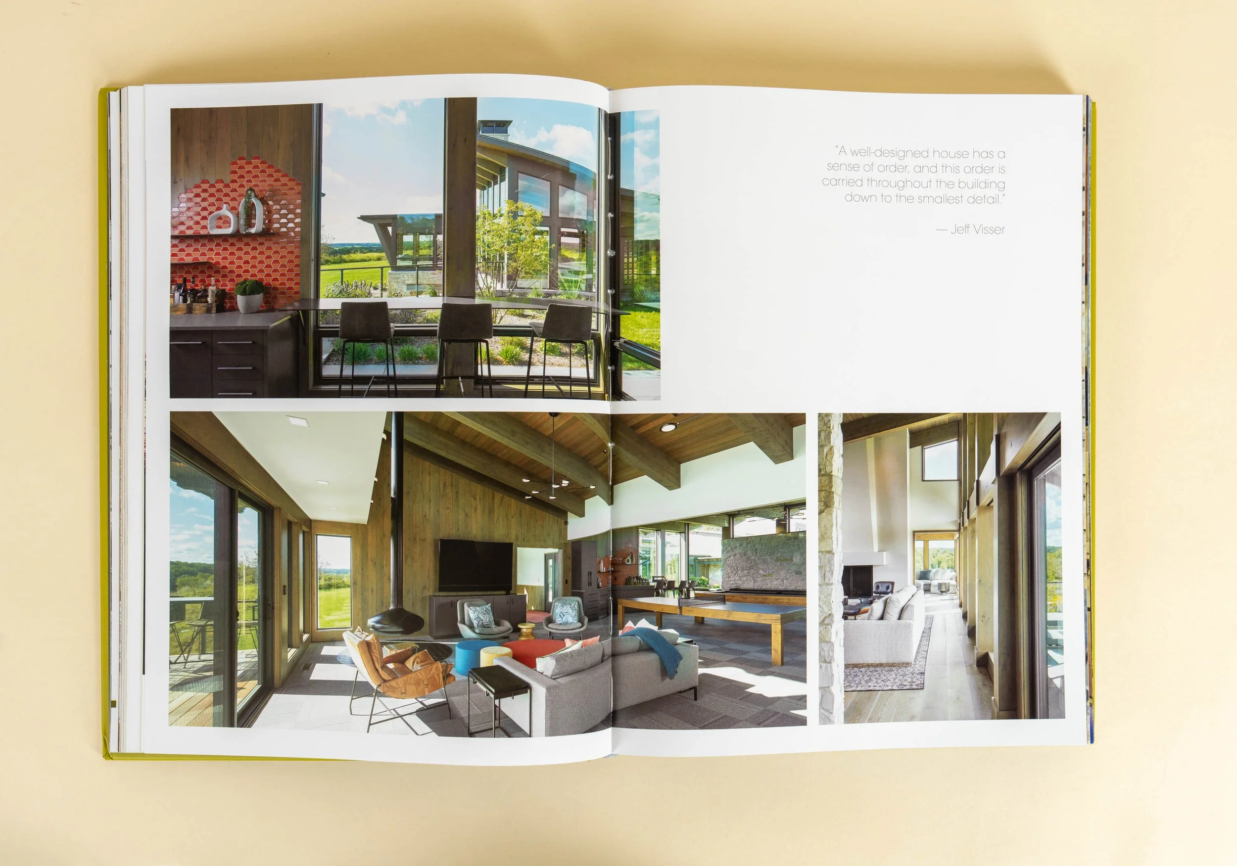 Open book showing photos of modern home interiors with large windows and wooden beams.