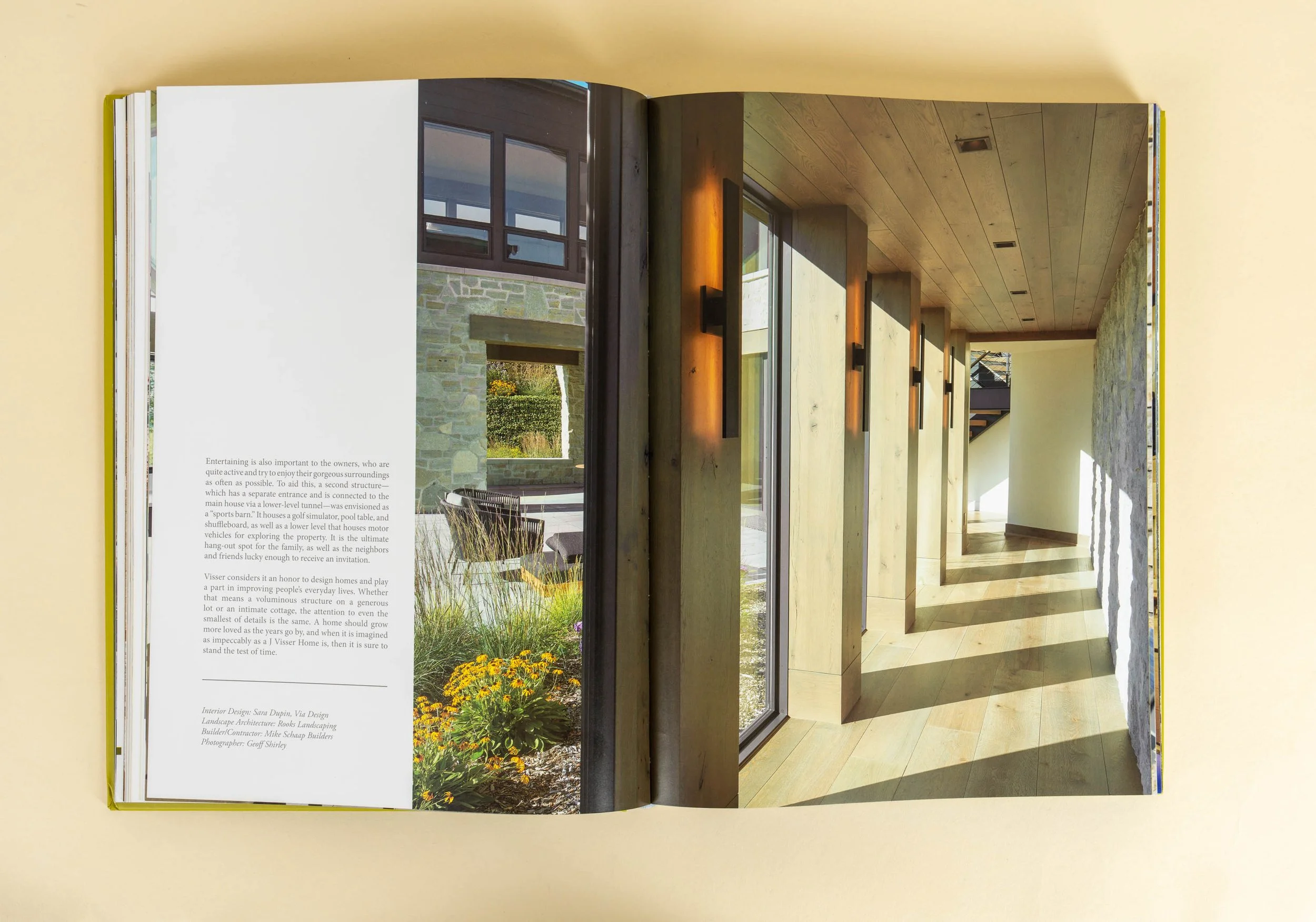 Open book showing a modern home corridor with floor-to-ceiling windows and sunlight casting shadows.