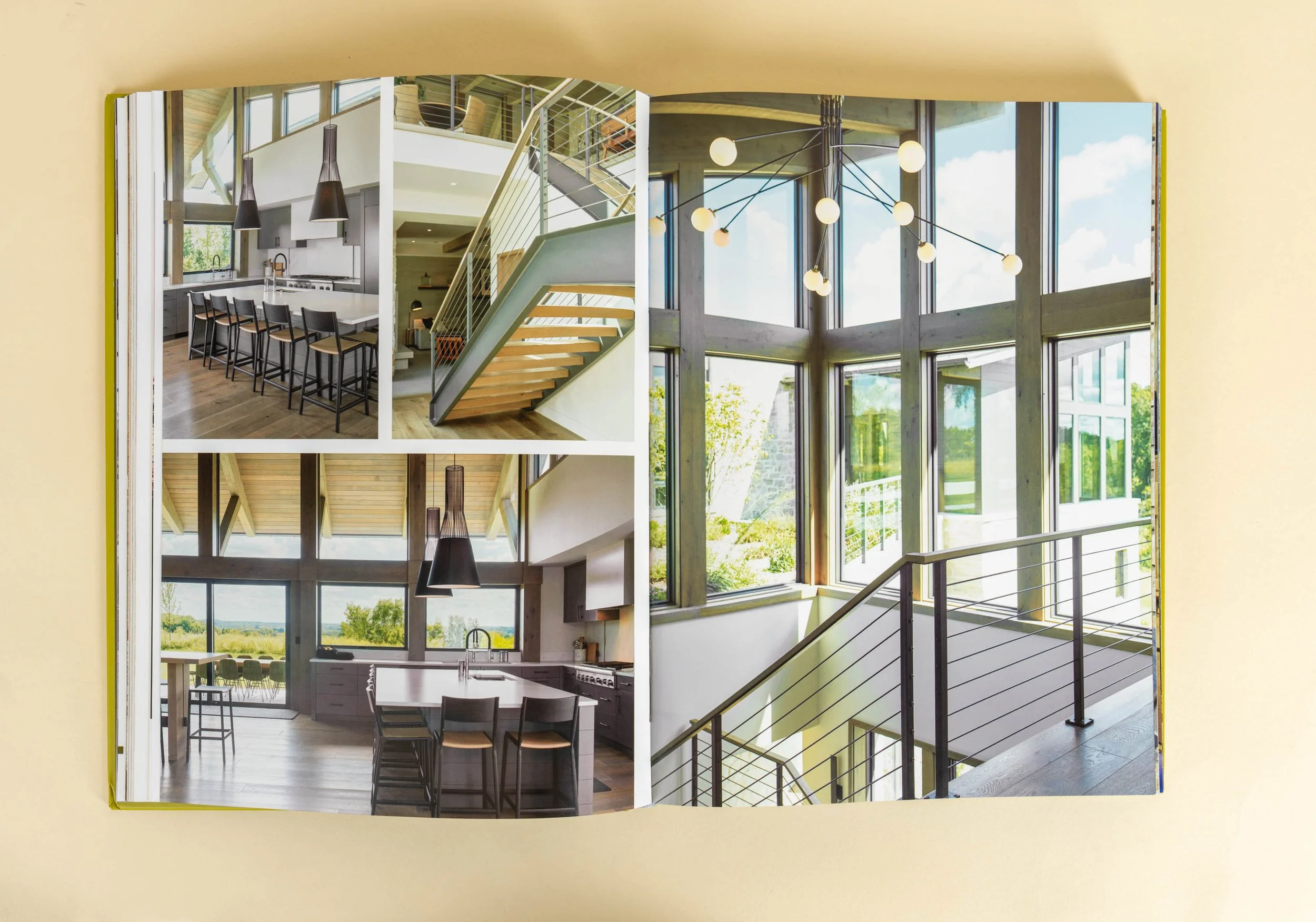 Modern interior with large windows, a kitchen island, hanging lights, and a metal staircase with wooden steps.