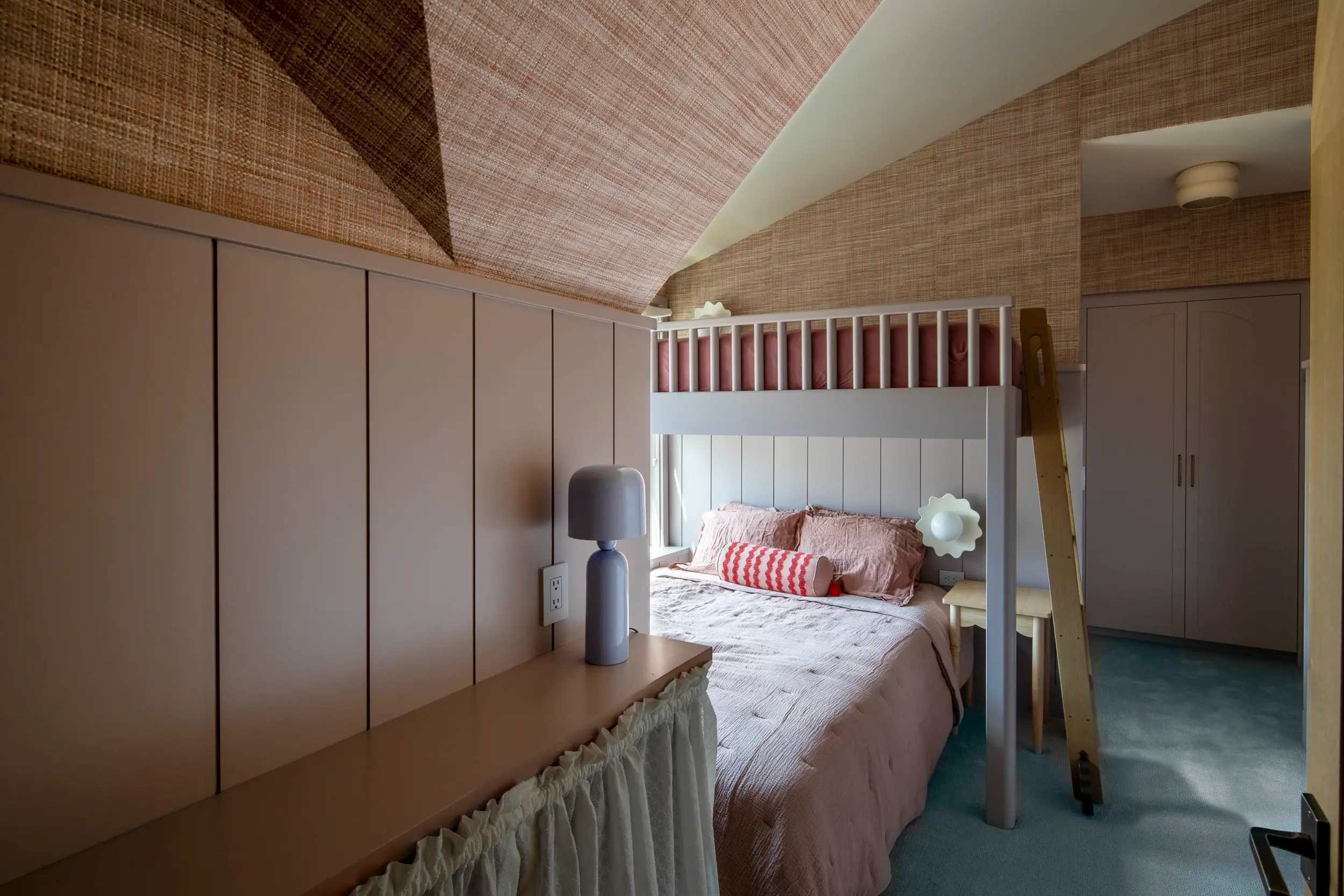 Cozy bedroom with loft bed over a double bed, wooden ladder, and beige walls with textured ceiling.