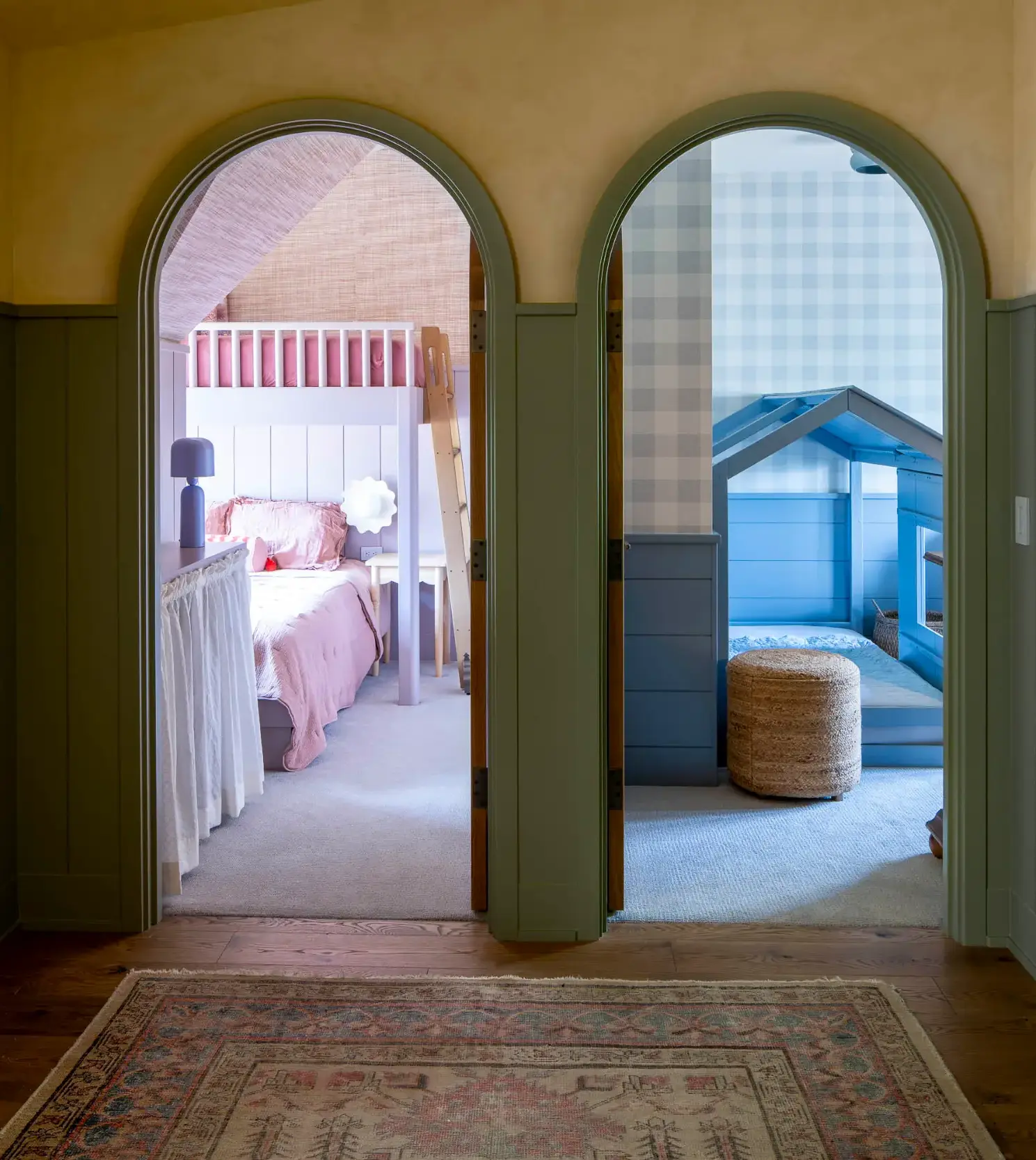 Two arched doorways leading to a pink bunk bed room on left and blue playhouse room on right.