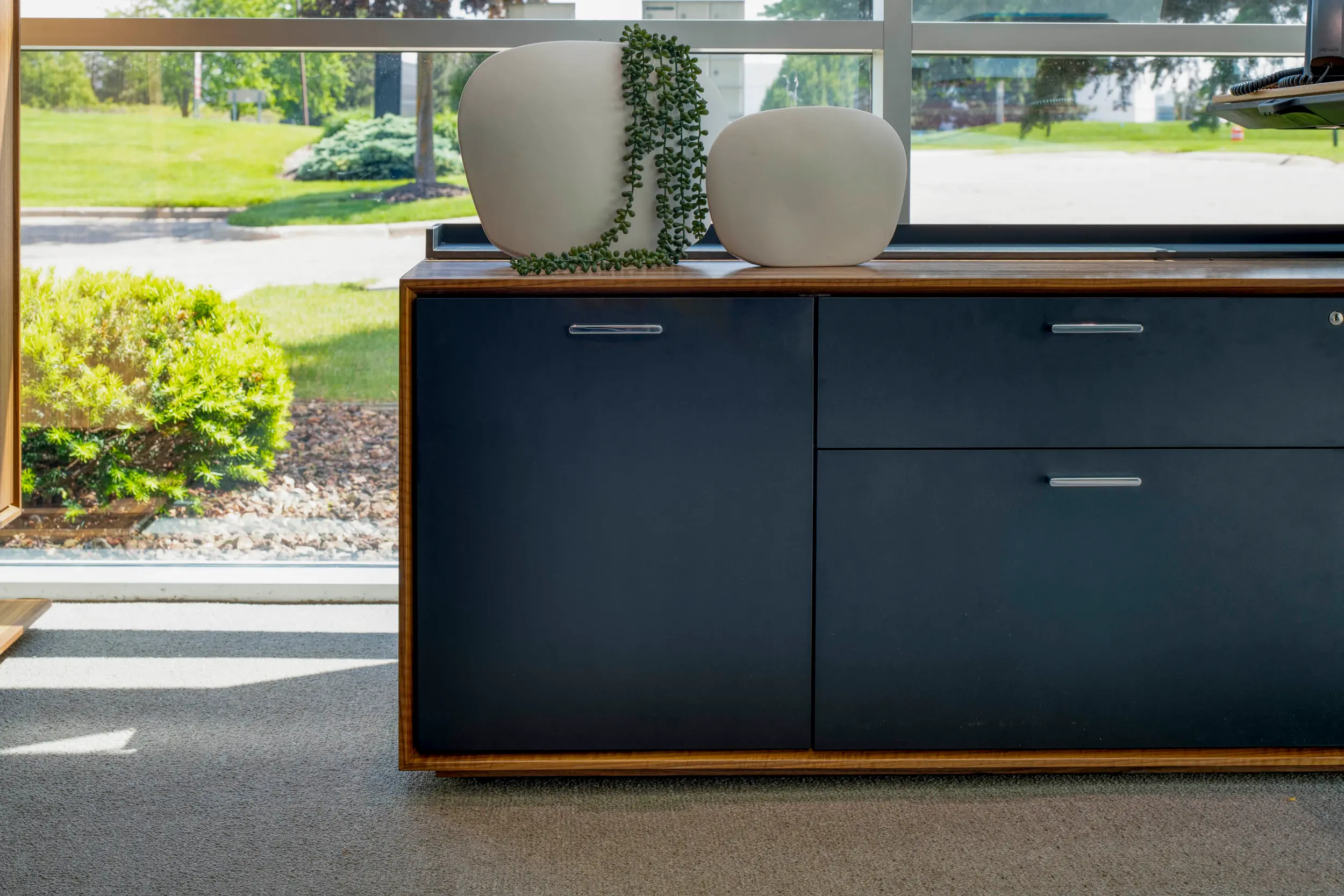 Modern sideboard with navy blue drawers topped with two white vases, one holding a trailing plant.