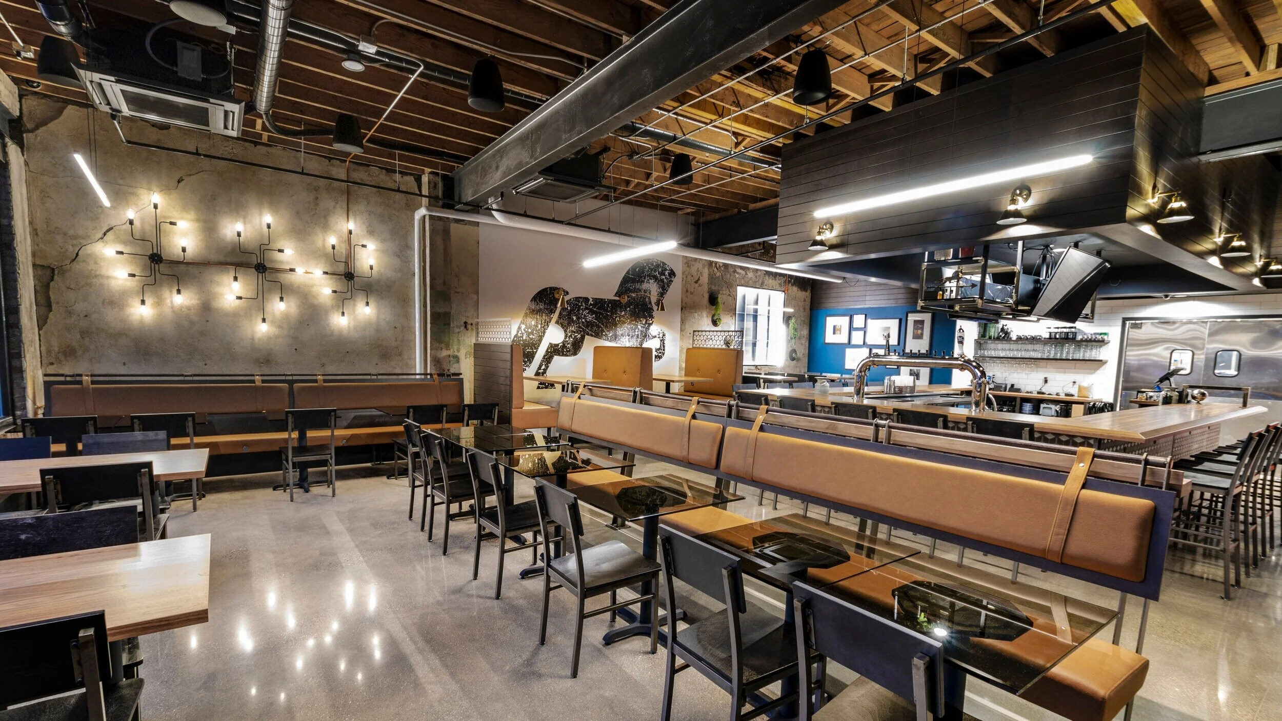 Modern restaurant interior with glass tables, brown bench seating, black chairs, and a large horse mural.