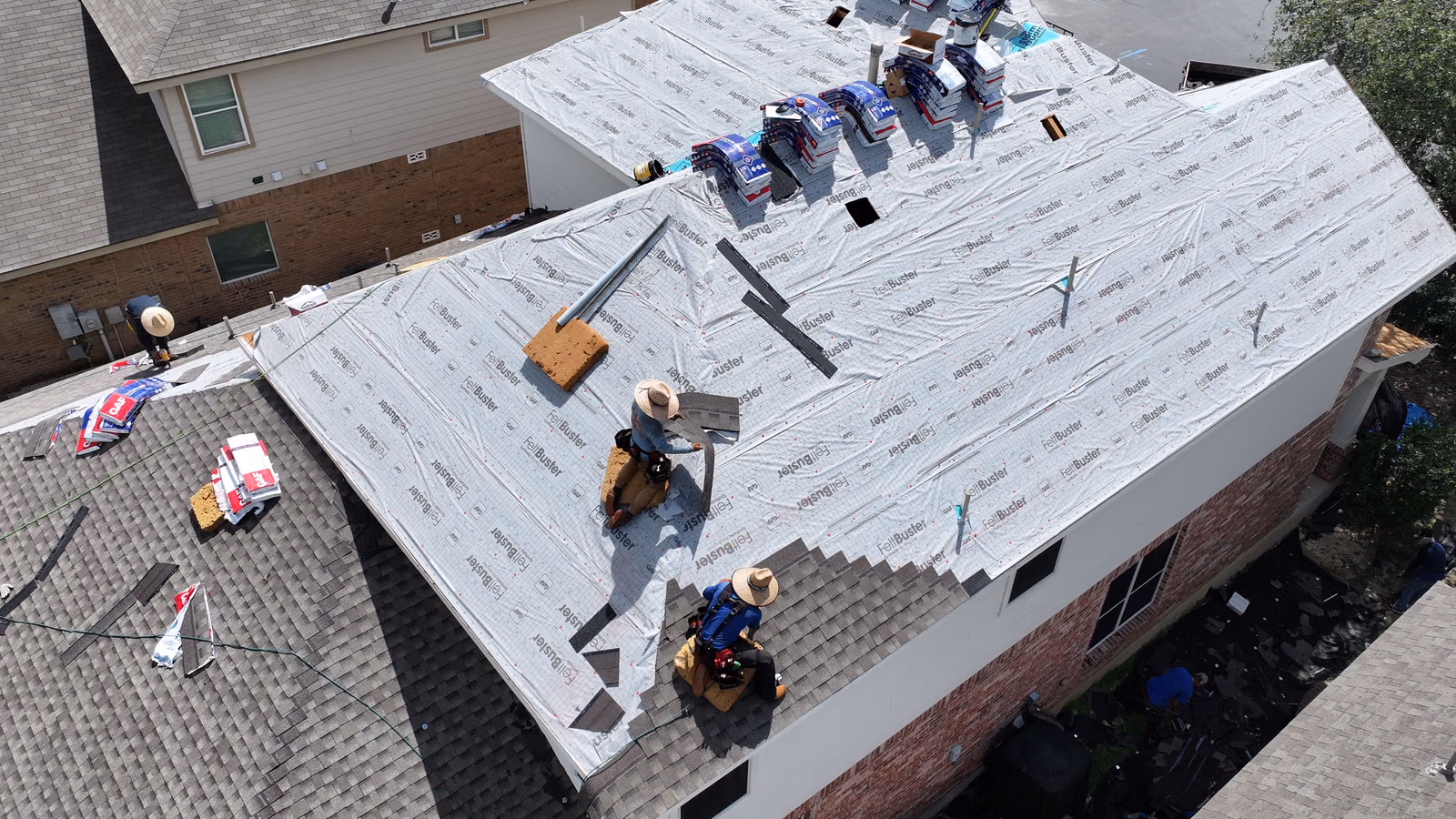 Roofing crew installing synthetic underlayment on a roof during a repair.