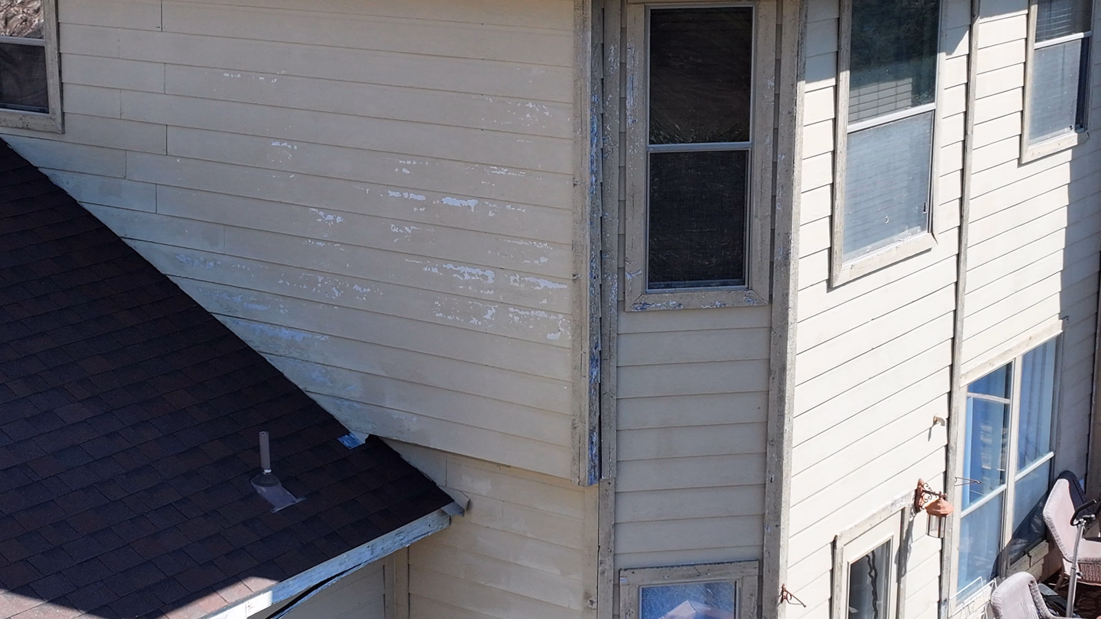 Corner of a house showing weathered, fading horizontal siding.