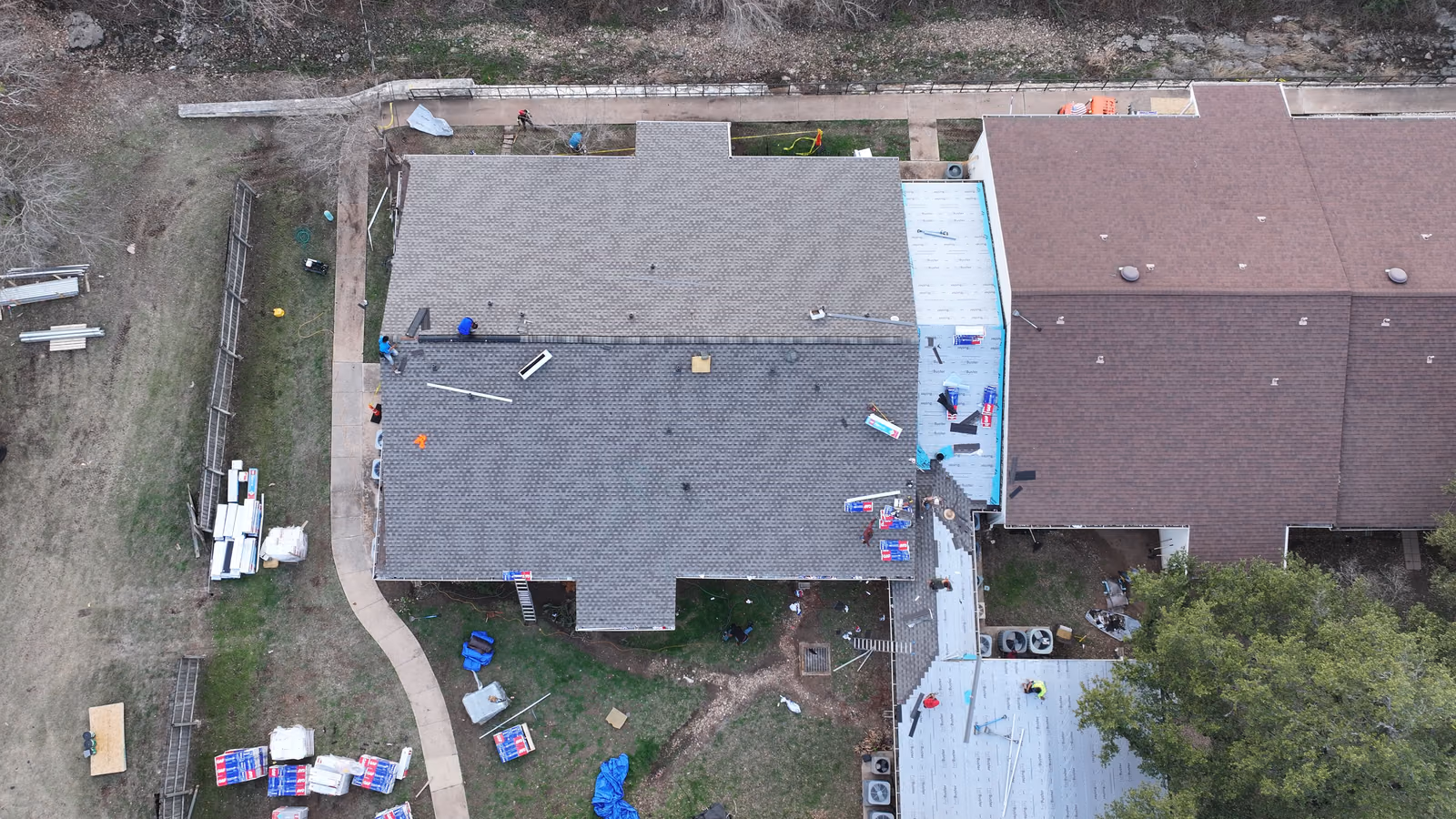 Roofing materials neatly staged in a driveway during a re-roofing project.