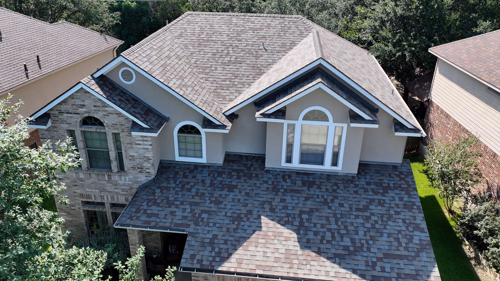 Aerial view of a large home with a finished gray shingle roof.