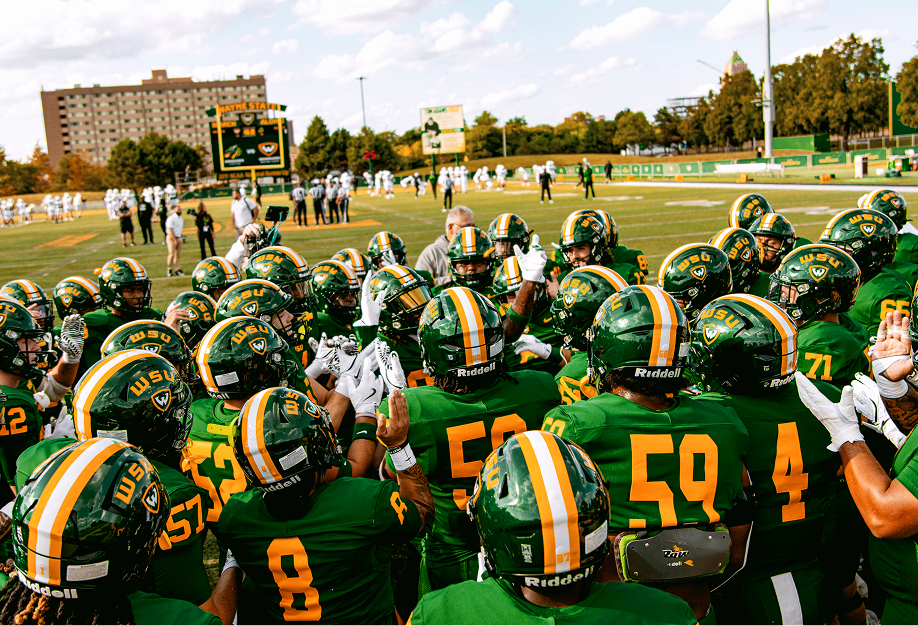 Wayne State football players huddle before a game at Tom Adams Field.