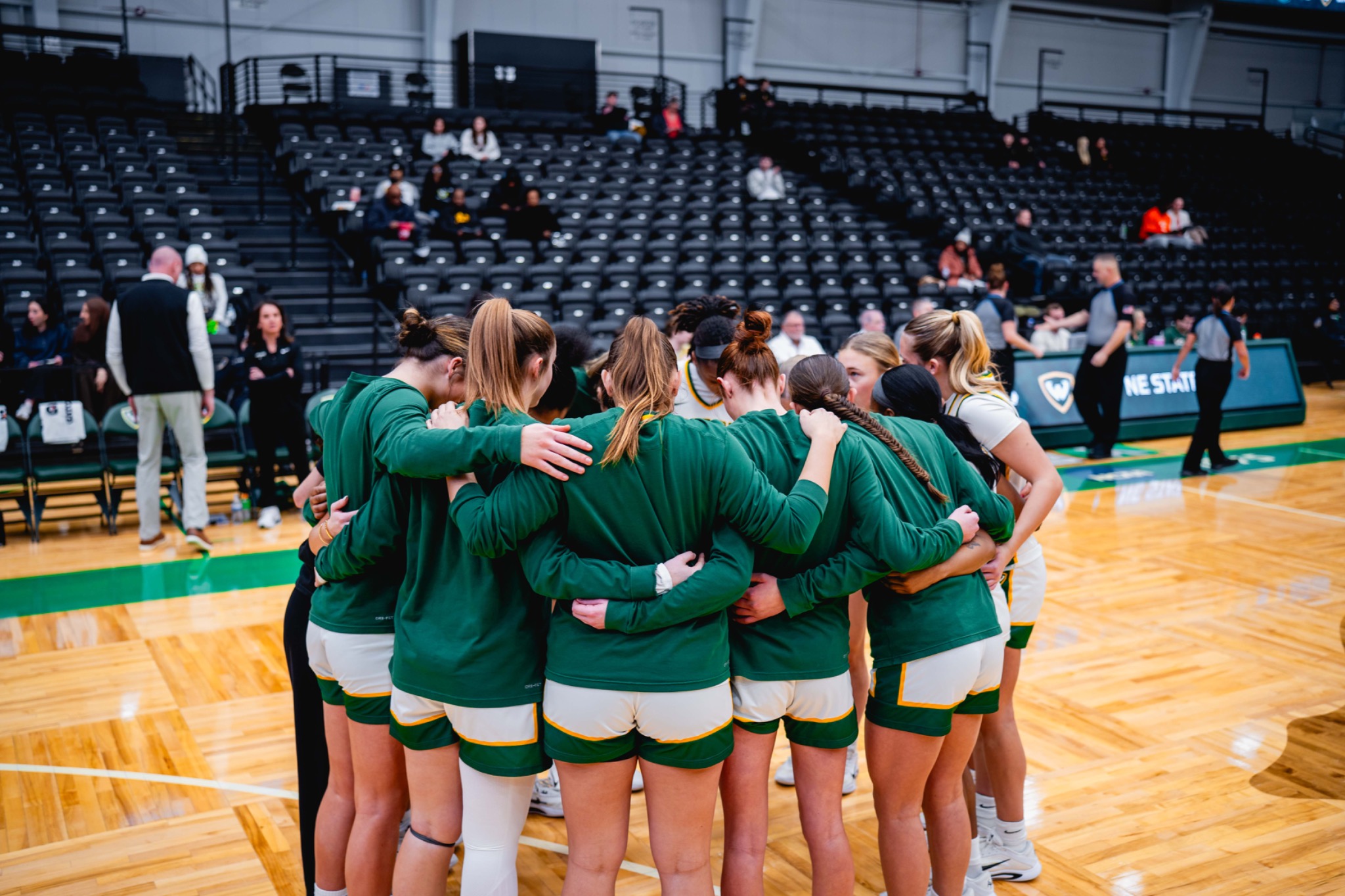 Wayne State women’s basketball players huddle on the home court.