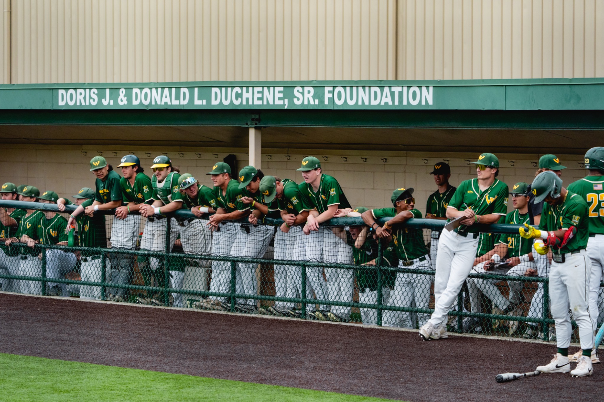 Wayne State baseball players line the home dugout.