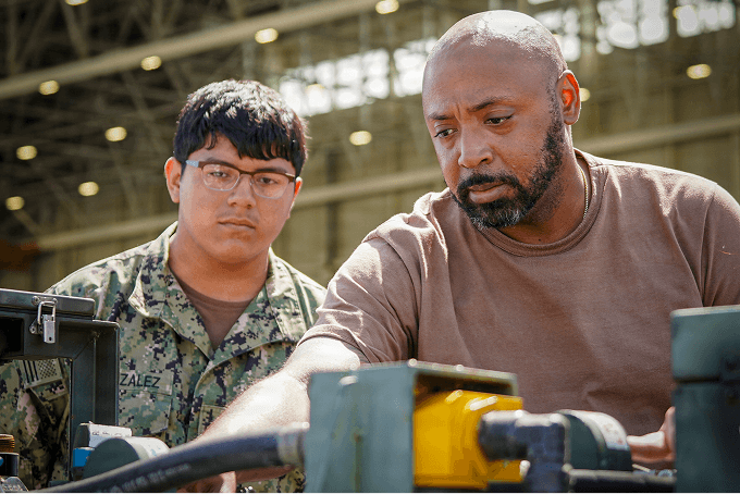 Mentor training a young apprentice on heavy equipment, building the next-generation workforce