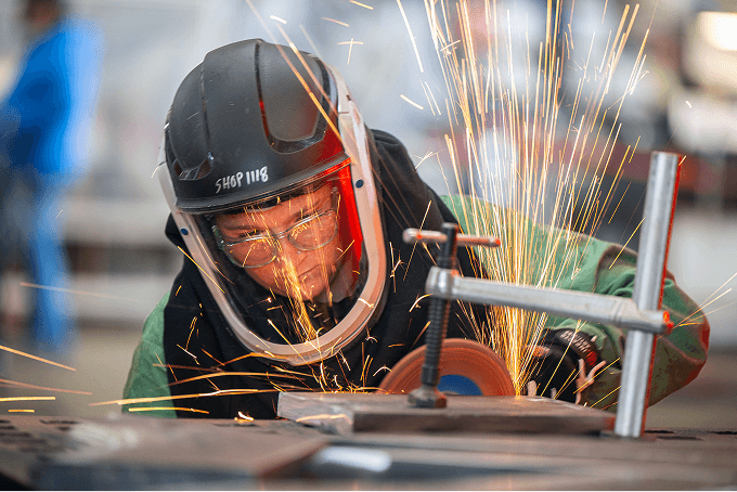 Skilled tradesperson grinding metal — hands-on work that automation can't replace
