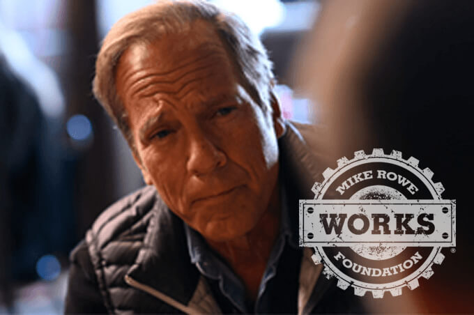 Mike Rowe in a dark jacket listening intently during a conversation