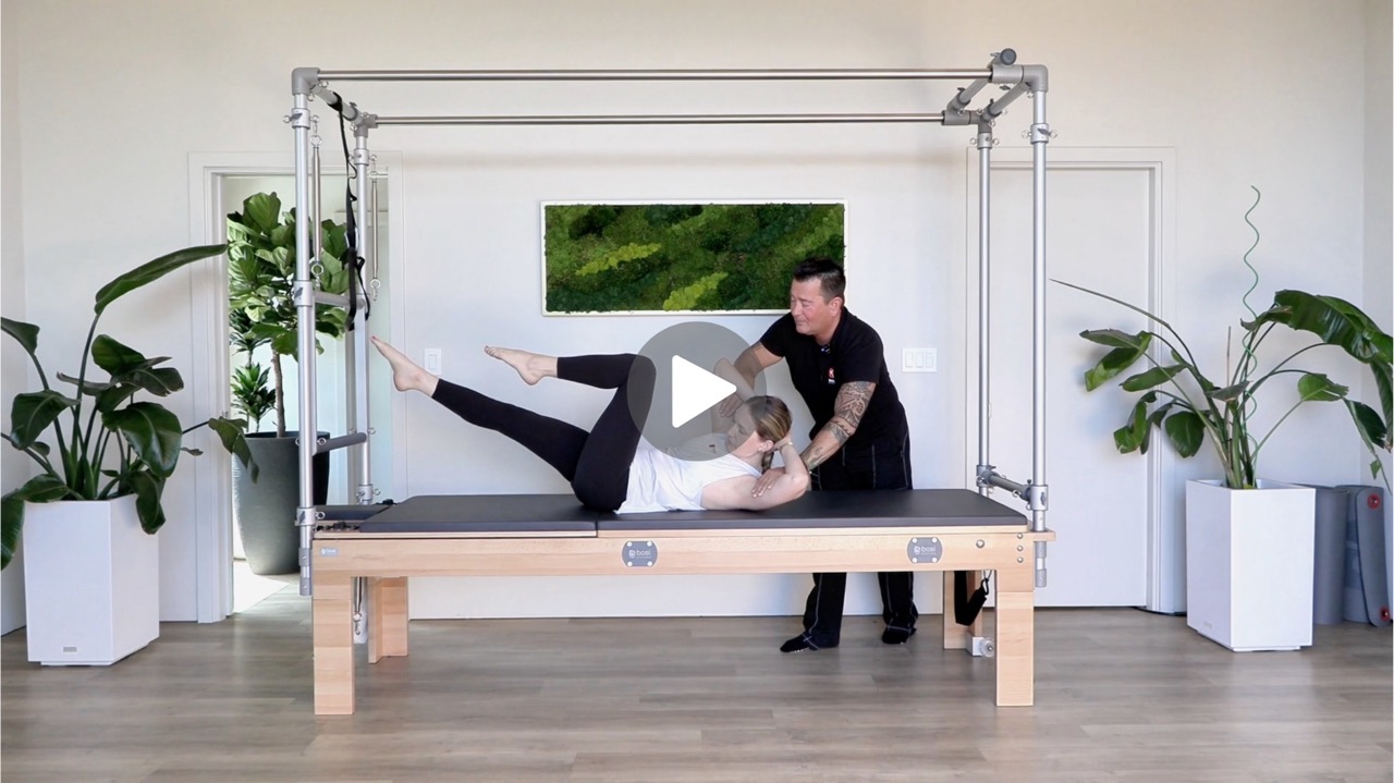 Image of male Pilates instructor cueing a student during Chest Lift with Rotation exercise.