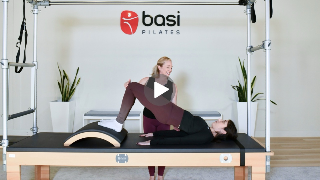 image of Pilates instructor helping a client perform an exercise.