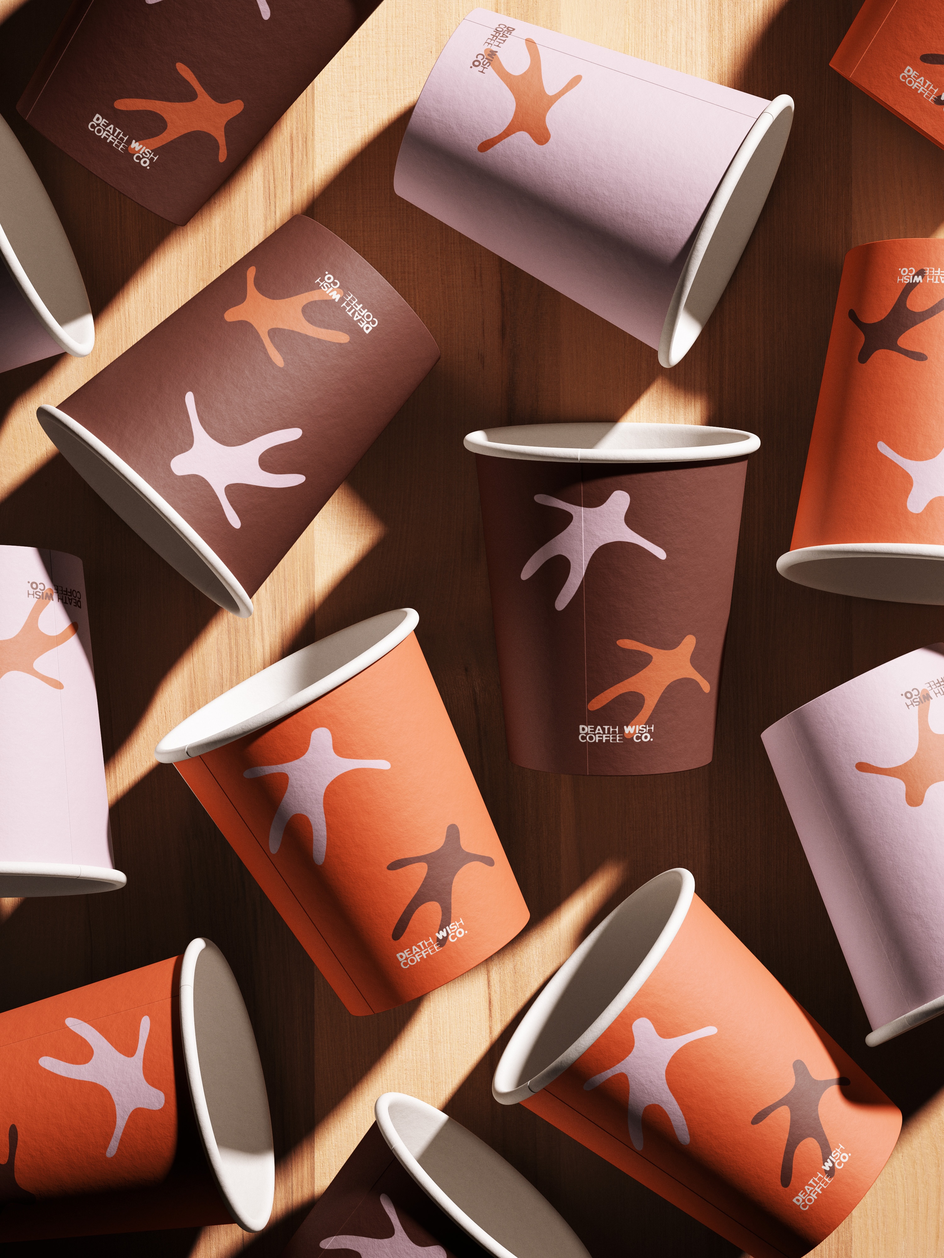 mockup found on magnific -Scattered colorful paper coffee cups with abstract shapes and Death Wish Coffee Co. logo on wooden surface.